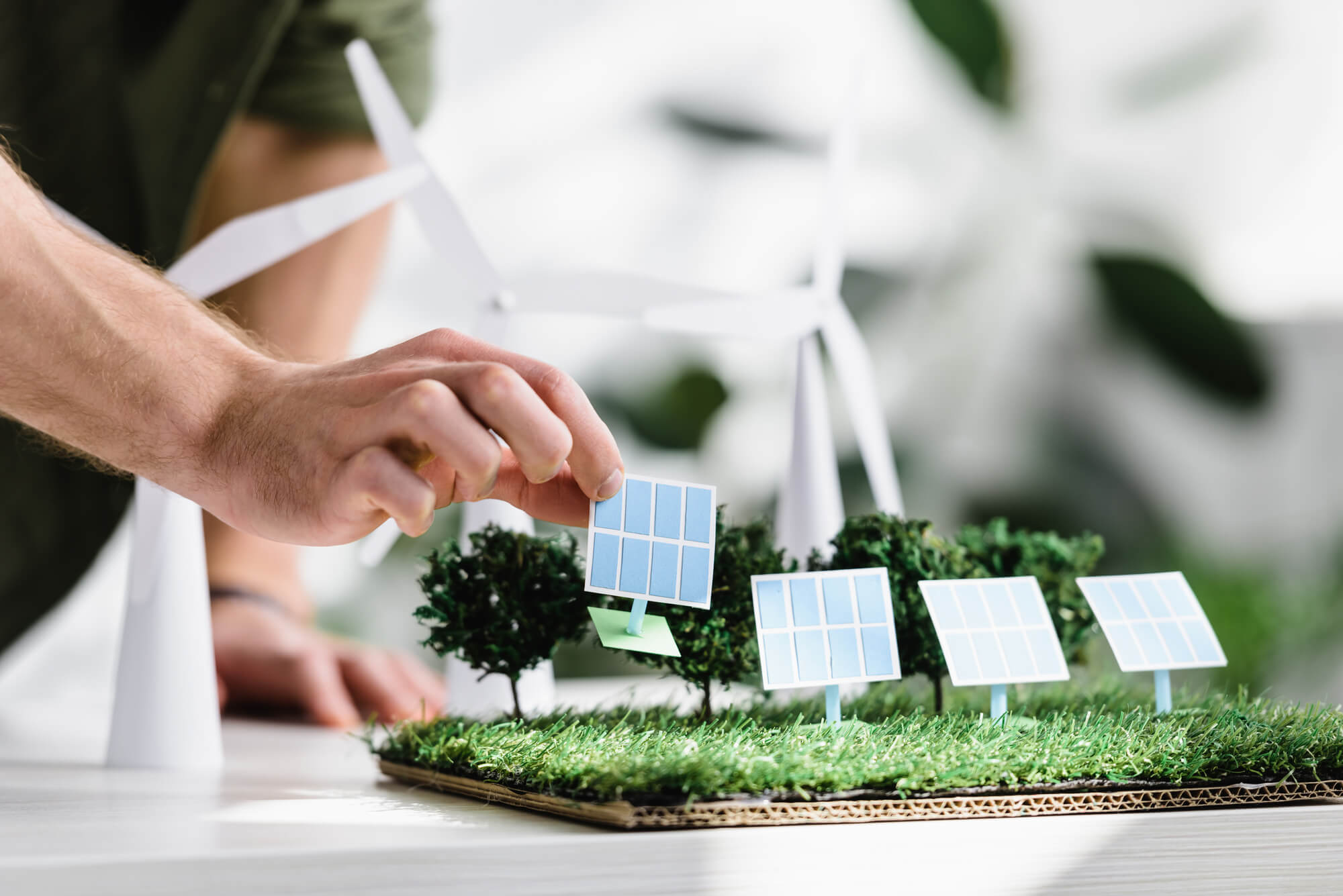 man placing solar panel models on grass