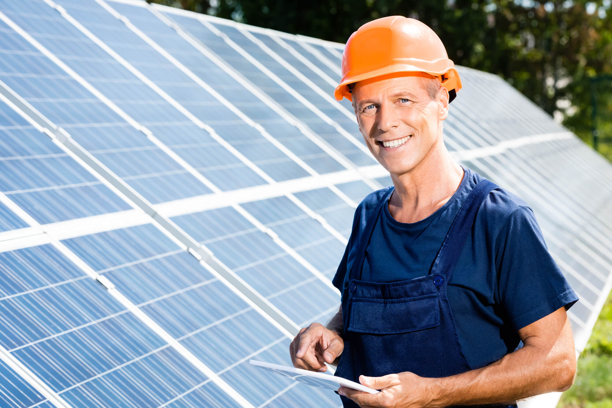 solar engineer smiling at camera while holding a tablet