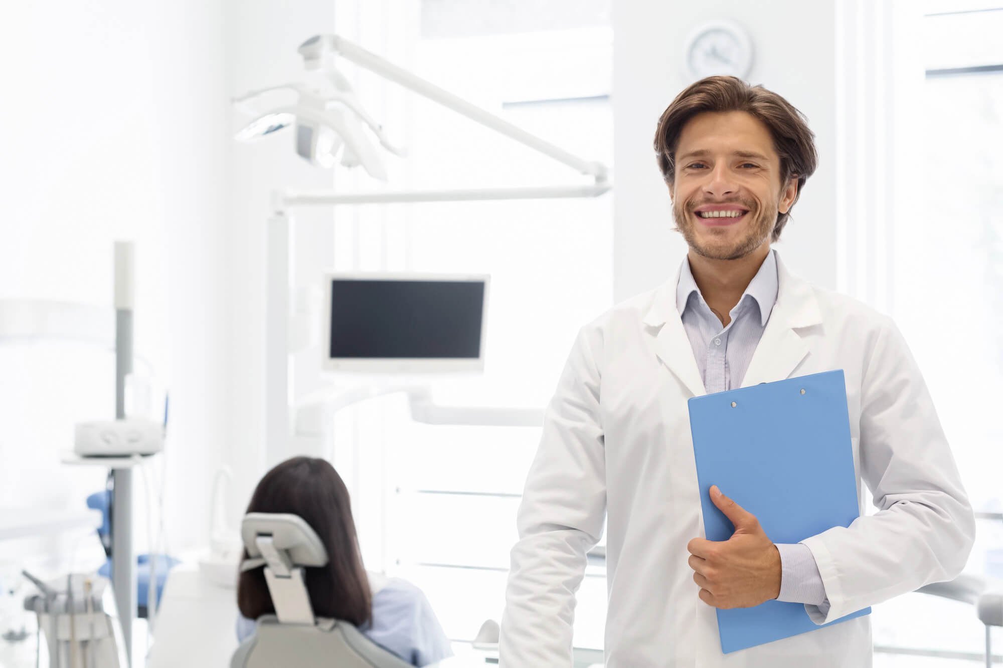 dentist smiling while holding a clipboard