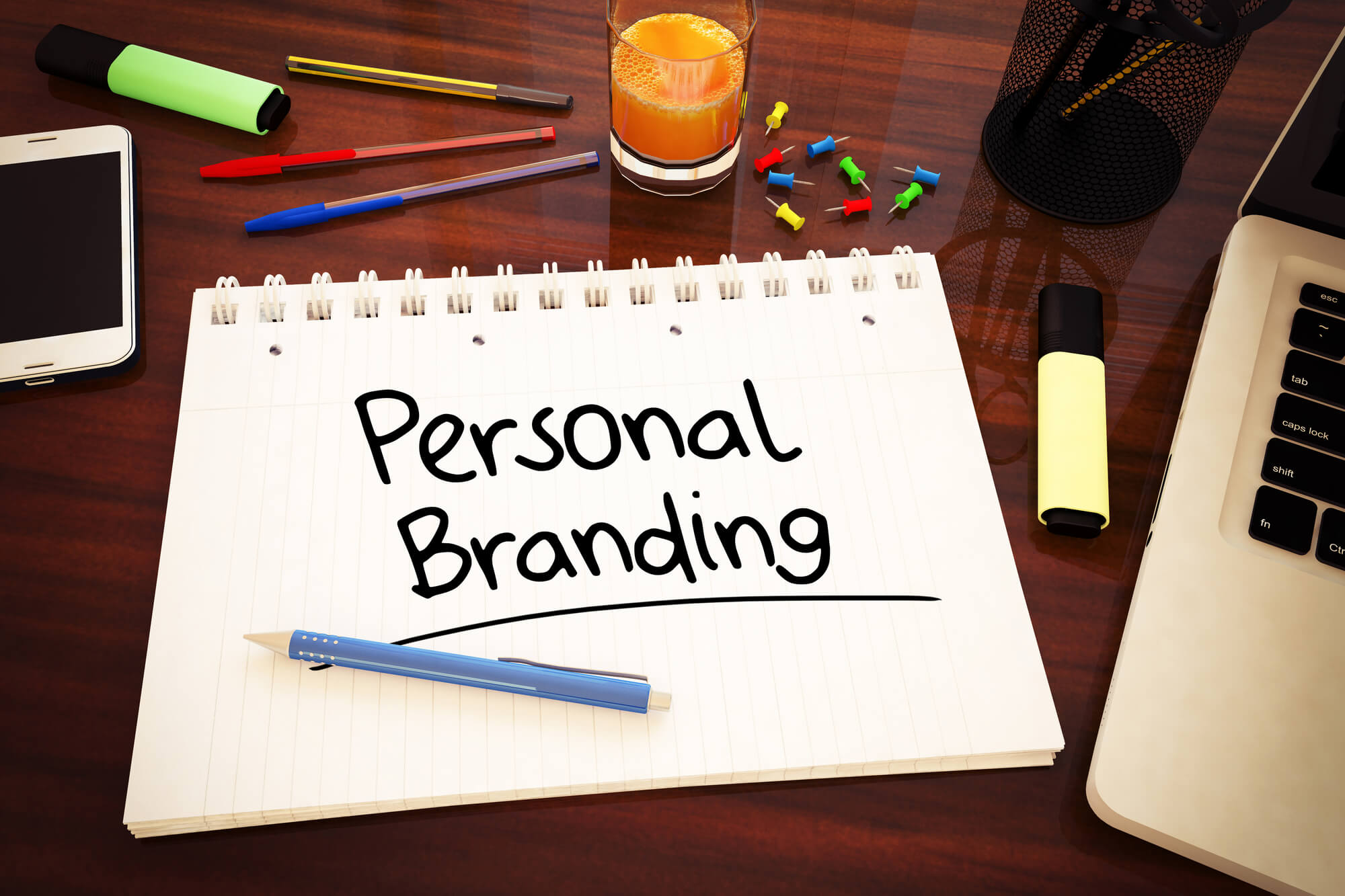 The word "personal branding" written on a notepad beside a laptop.
