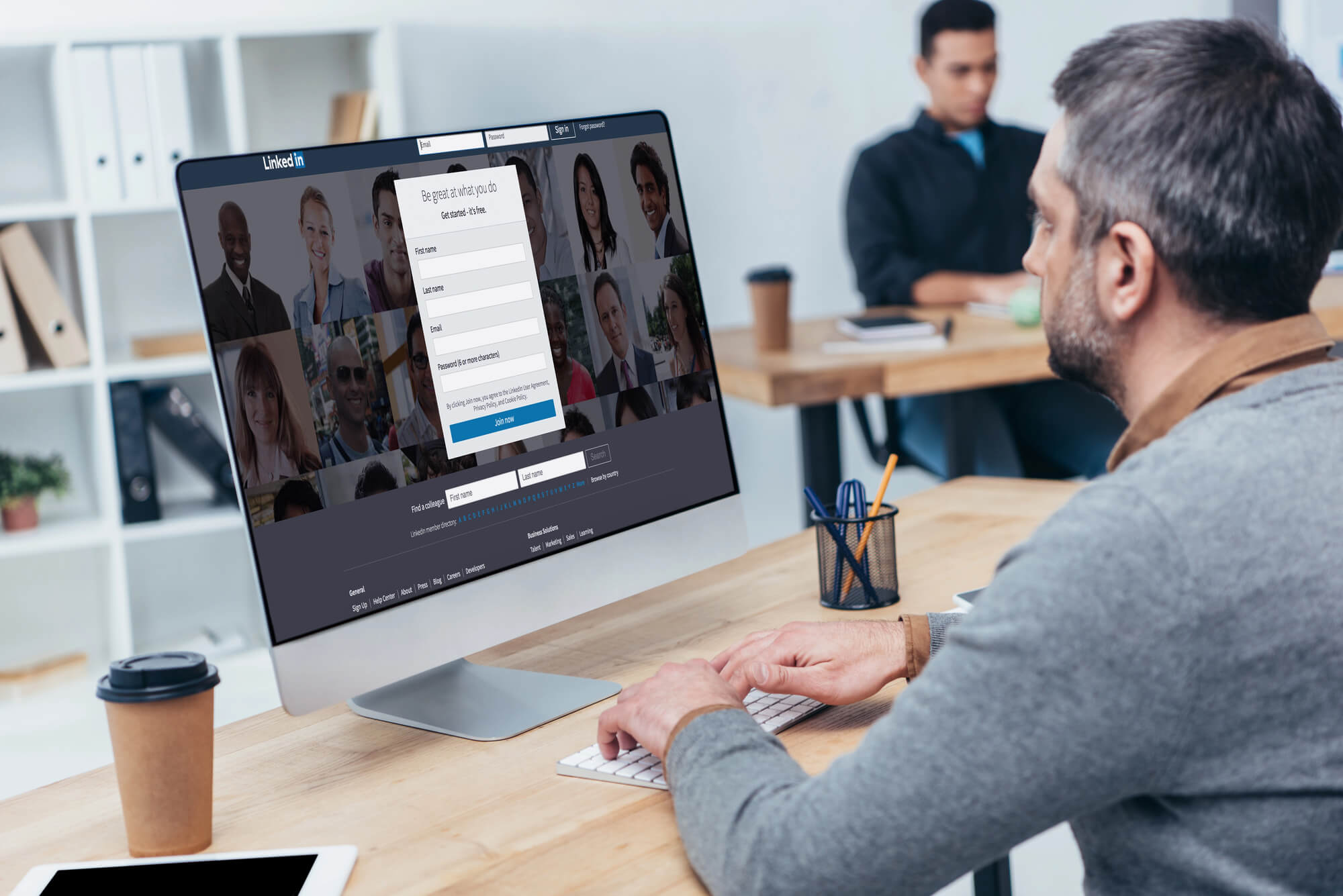 A man using a desktop computer with LinkedIn sign-up page open