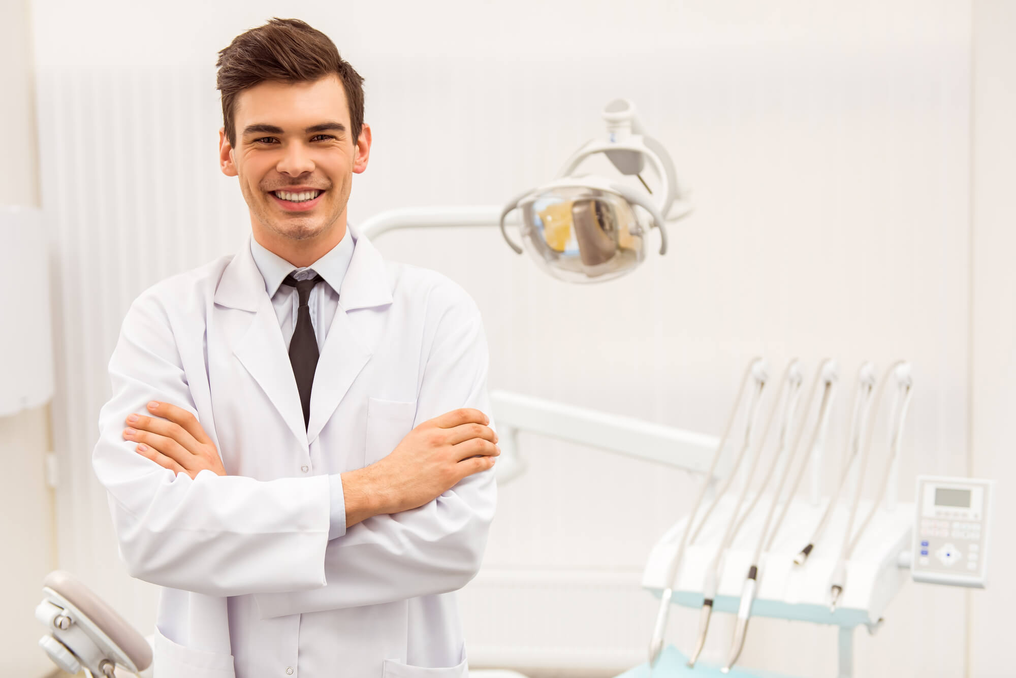 young male dentist smiling with arms crossed