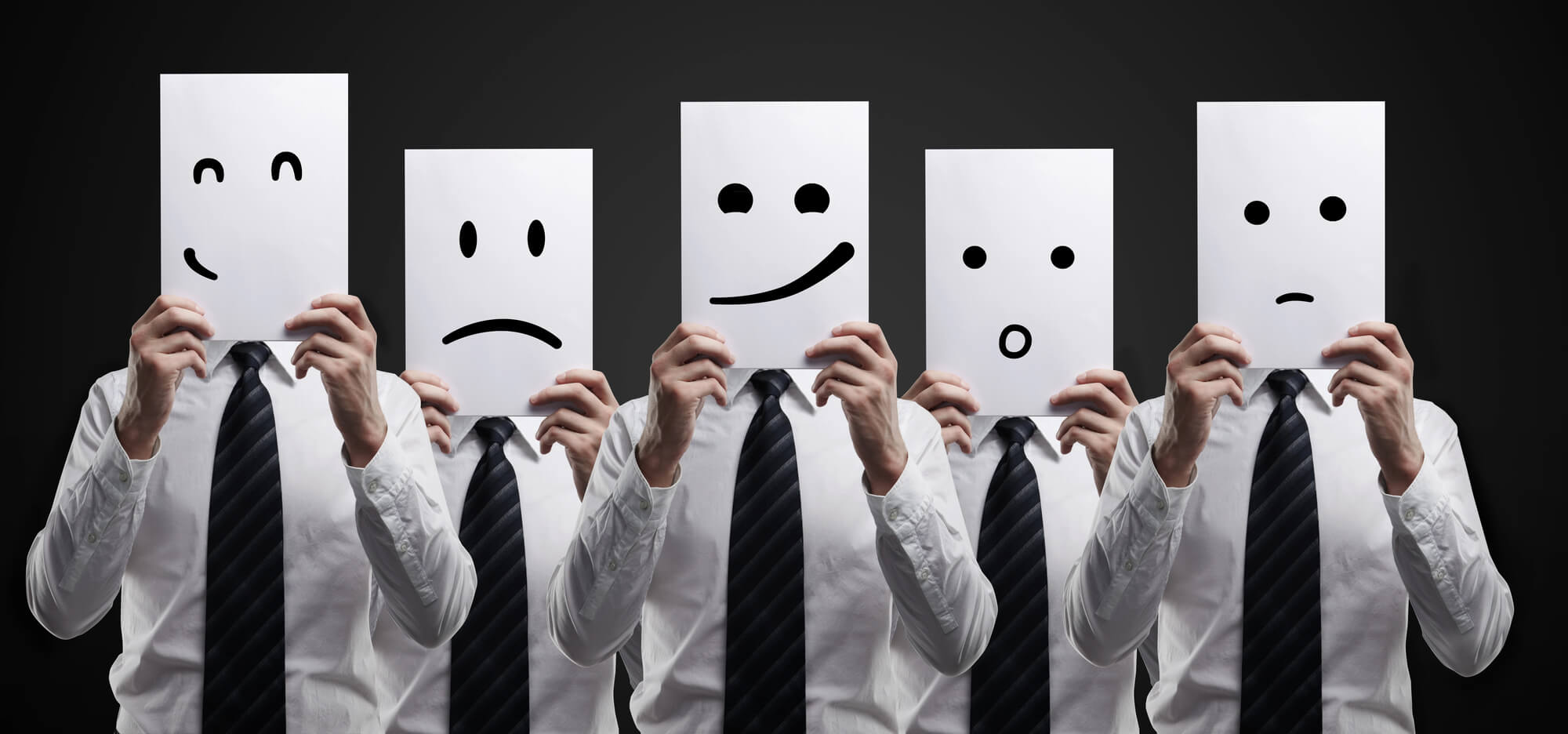 five businessmen holding cards with drawings of different emotions