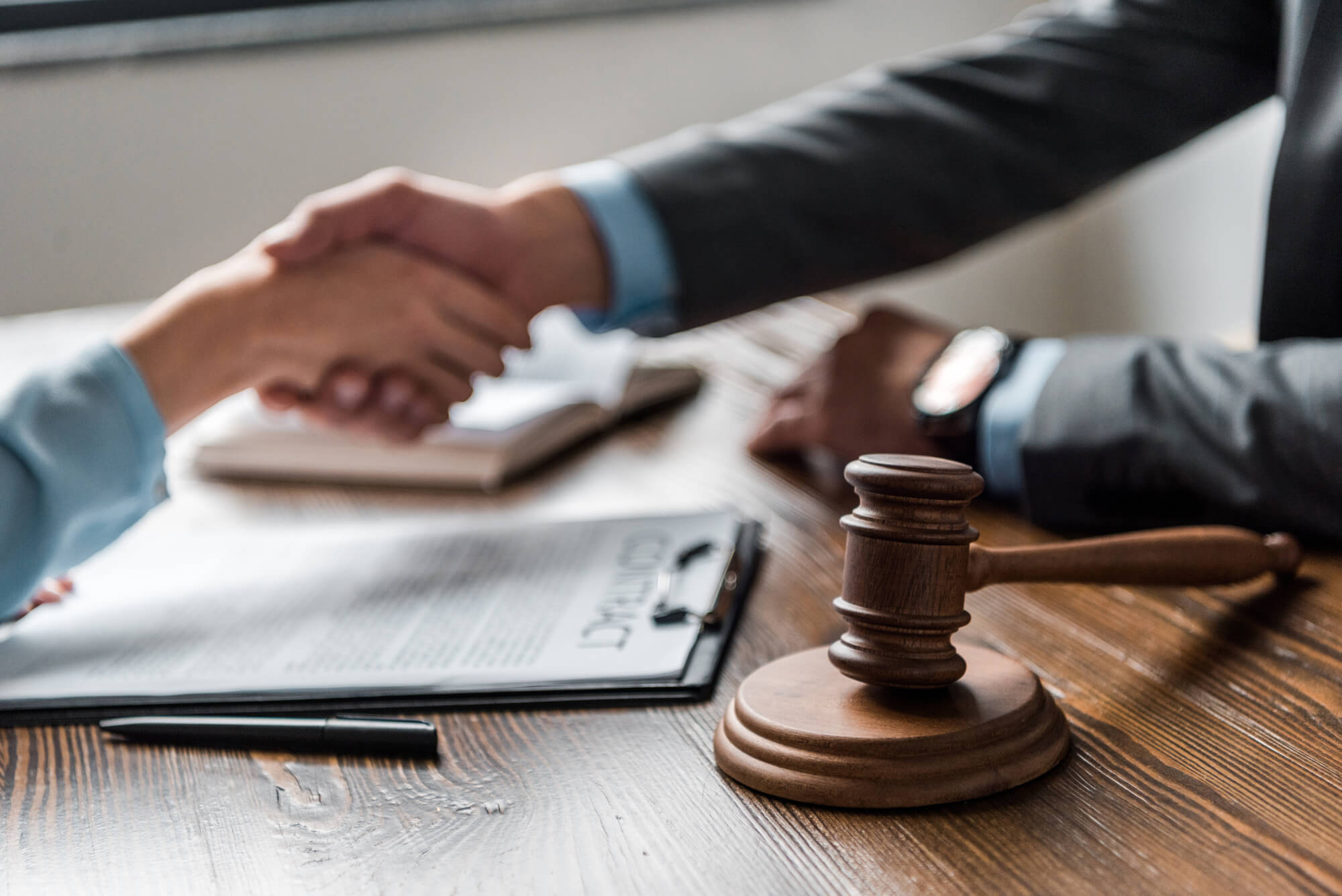 gavel with two hands shaking on the background and a clipboard