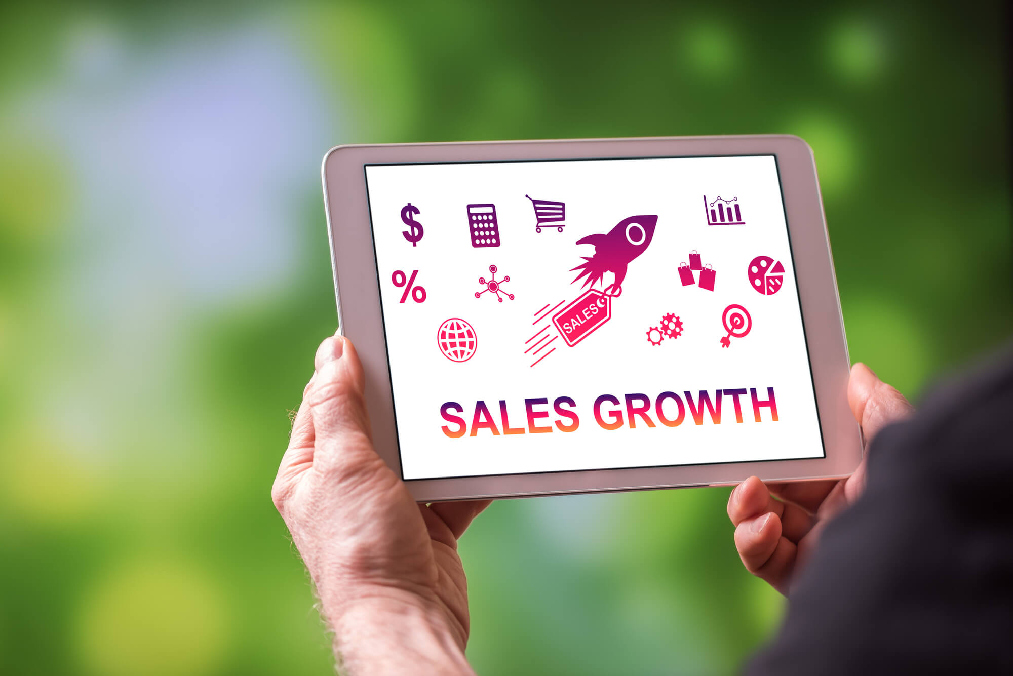 man holding tablet that displays sales growth on screen
