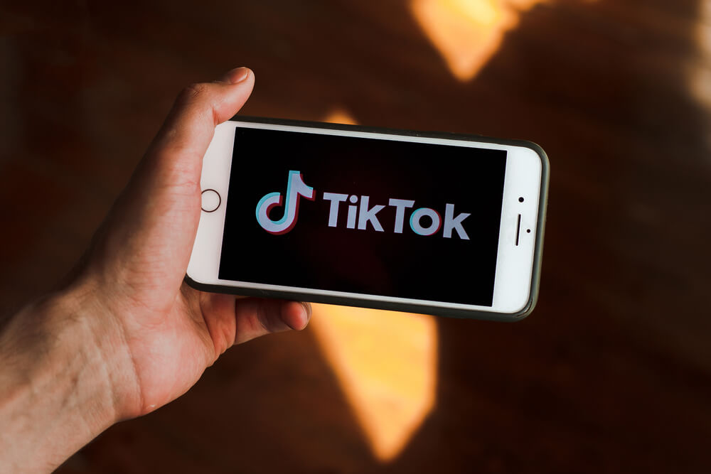Male hand holding phone with TikTok logo