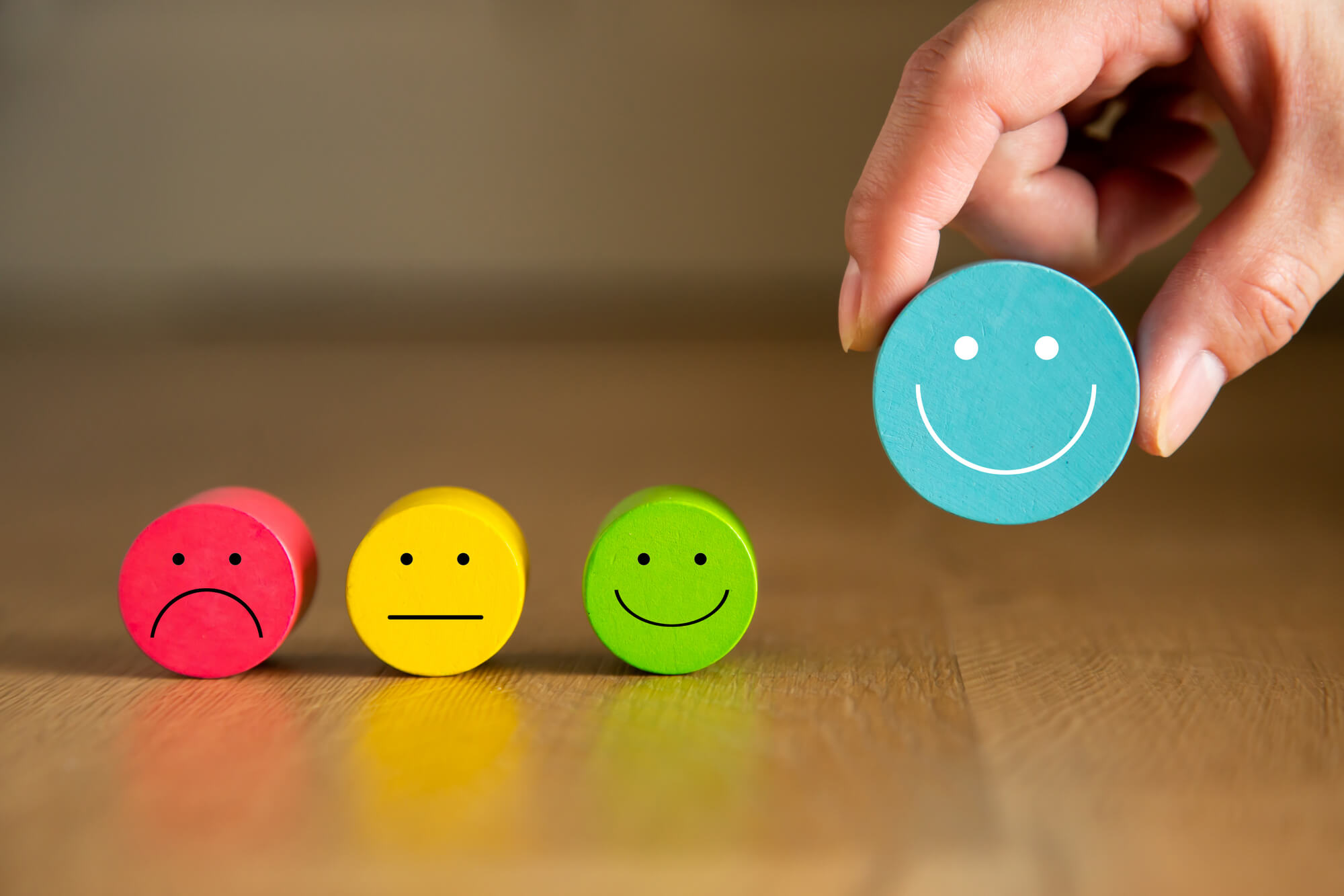 hand picking up smiley face over other emotions