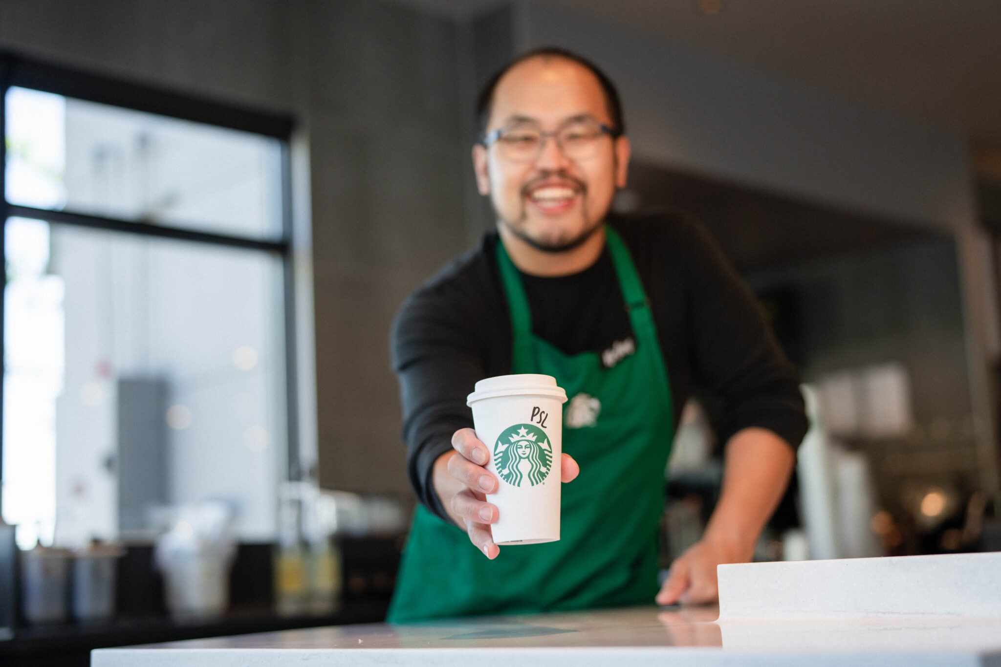 Starbucks barista giving a PSL order to a customer 
