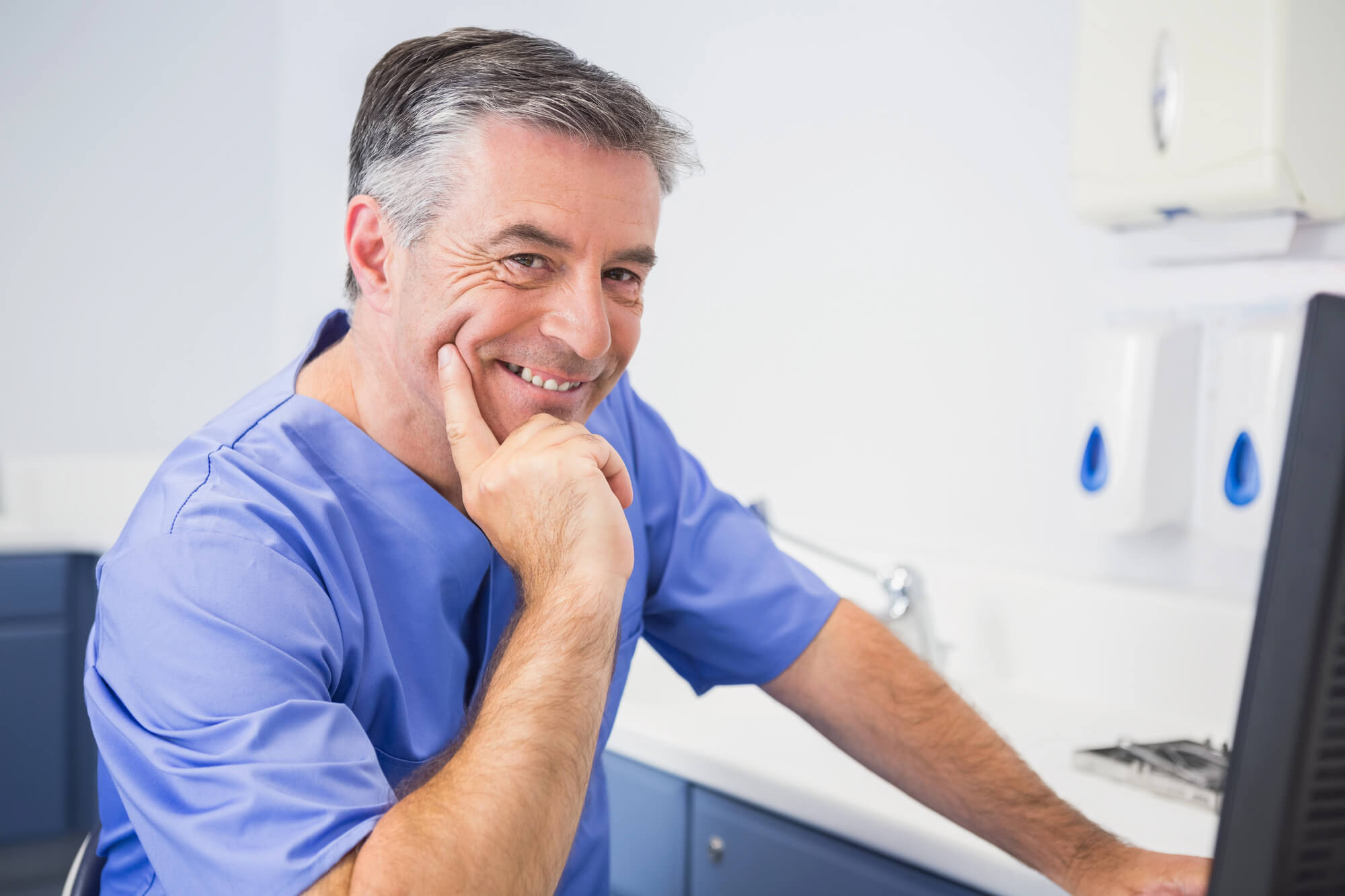 dentist smiling while facing his computer