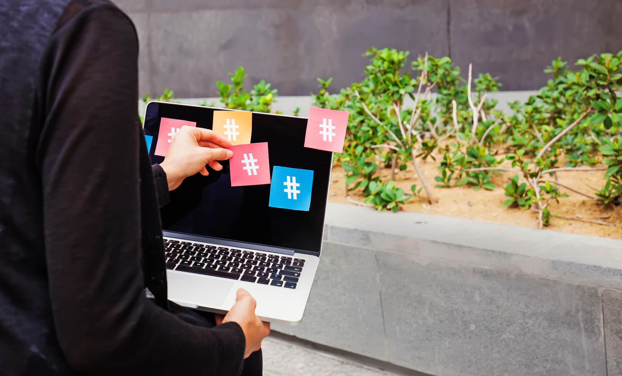 businesswoman attaching paper hashtags on her laptop screen