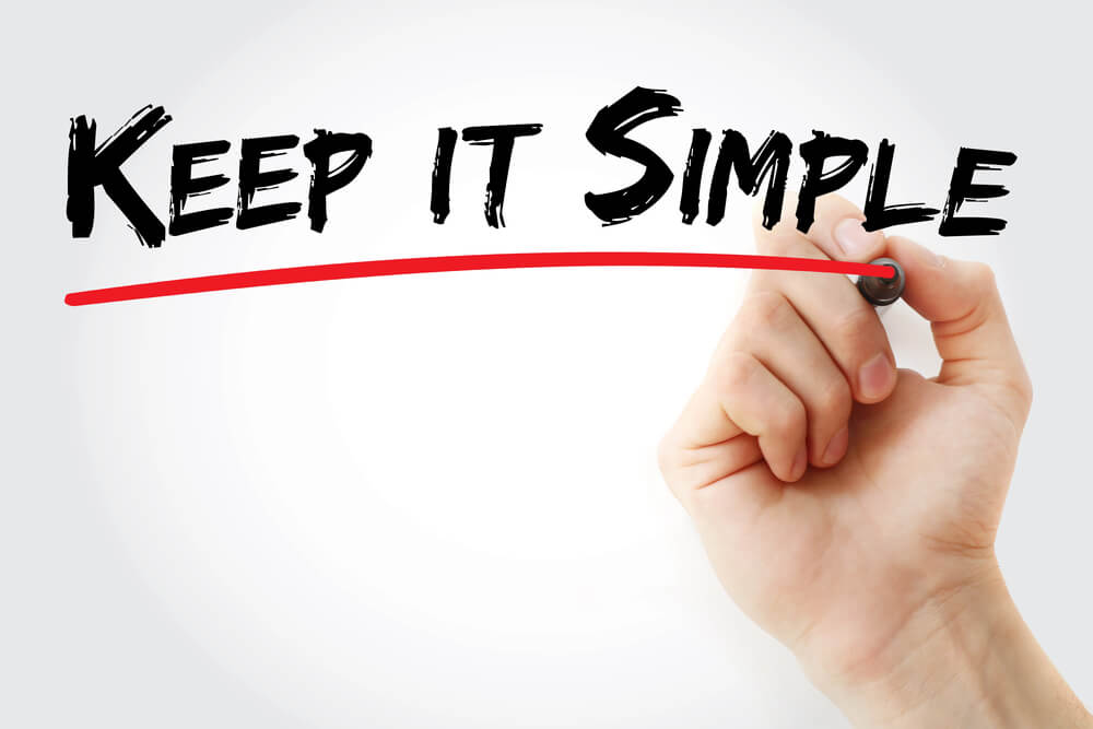 Hand writing "KEEP IT SIMPLE" on whiteboard