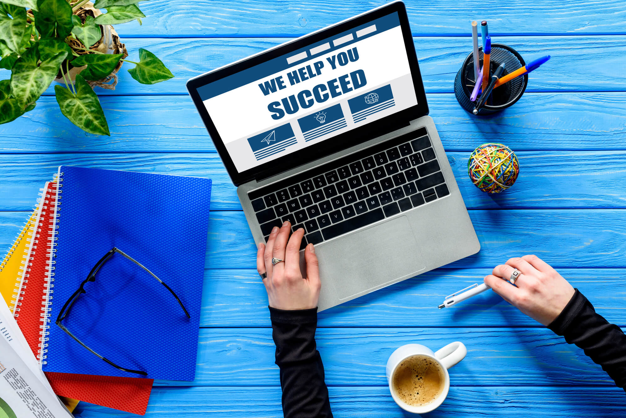 Person works on a laptop with "We Help You Succeed" on screen