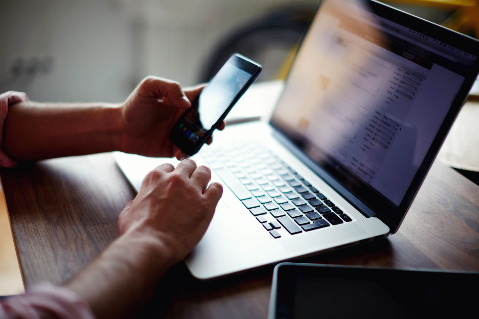 man using phone while working on laptop