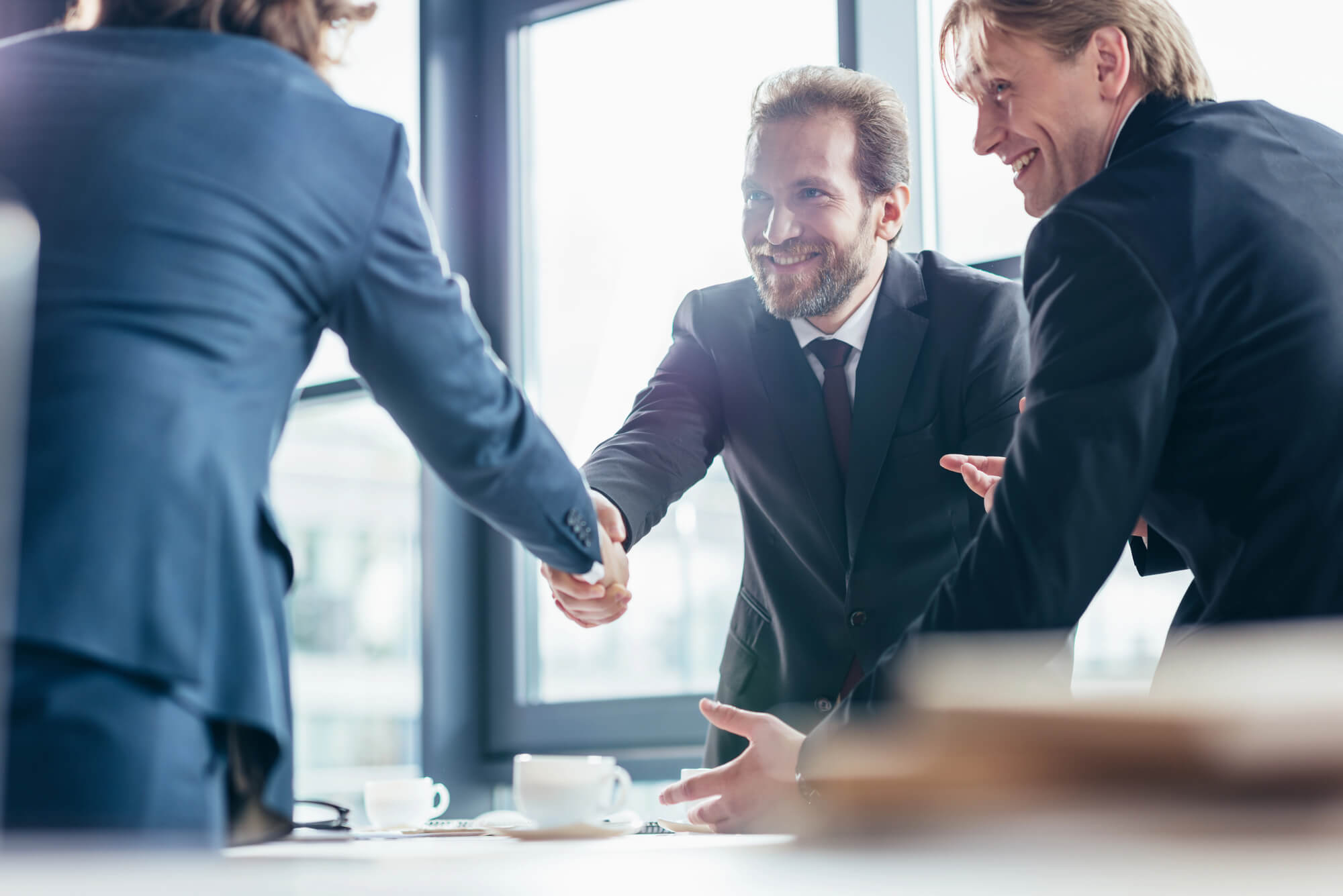 business professionals in suits shaking hands during a meeting, symbolizing agreement