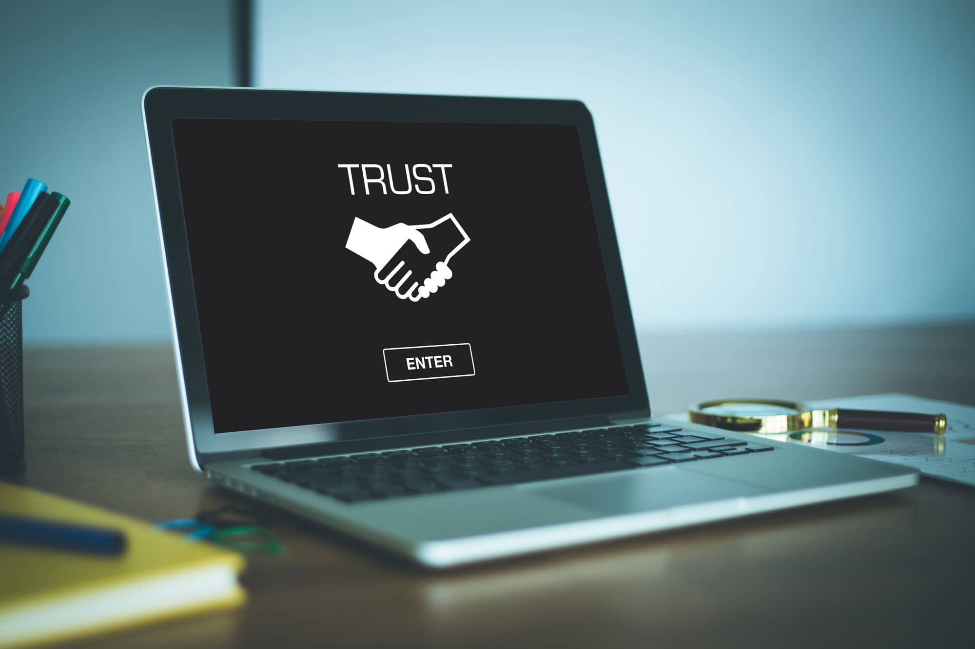 laptop displaying logo of a handshake with word trust above