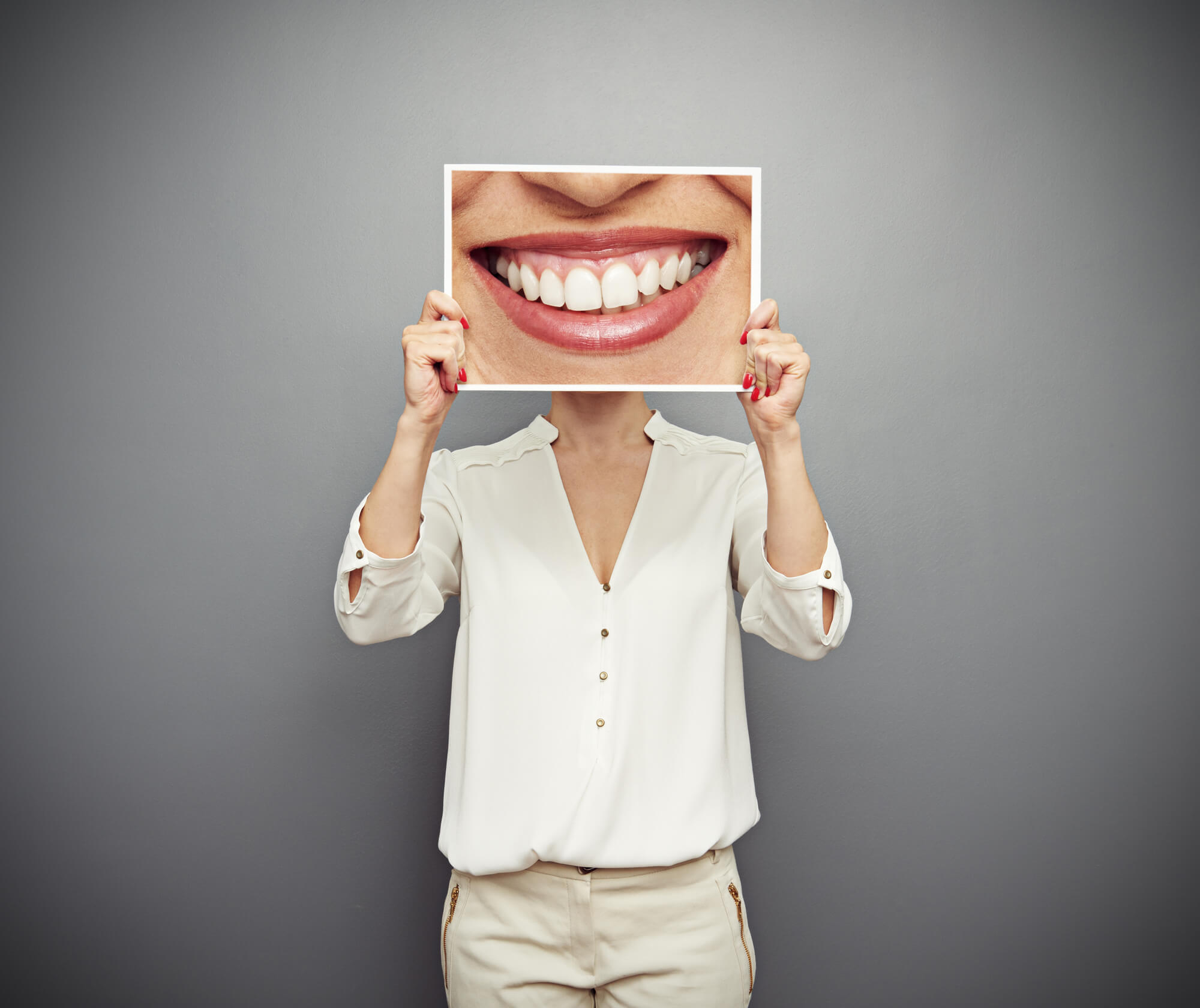 woman covering her face with a huge photo of her dazzling smile