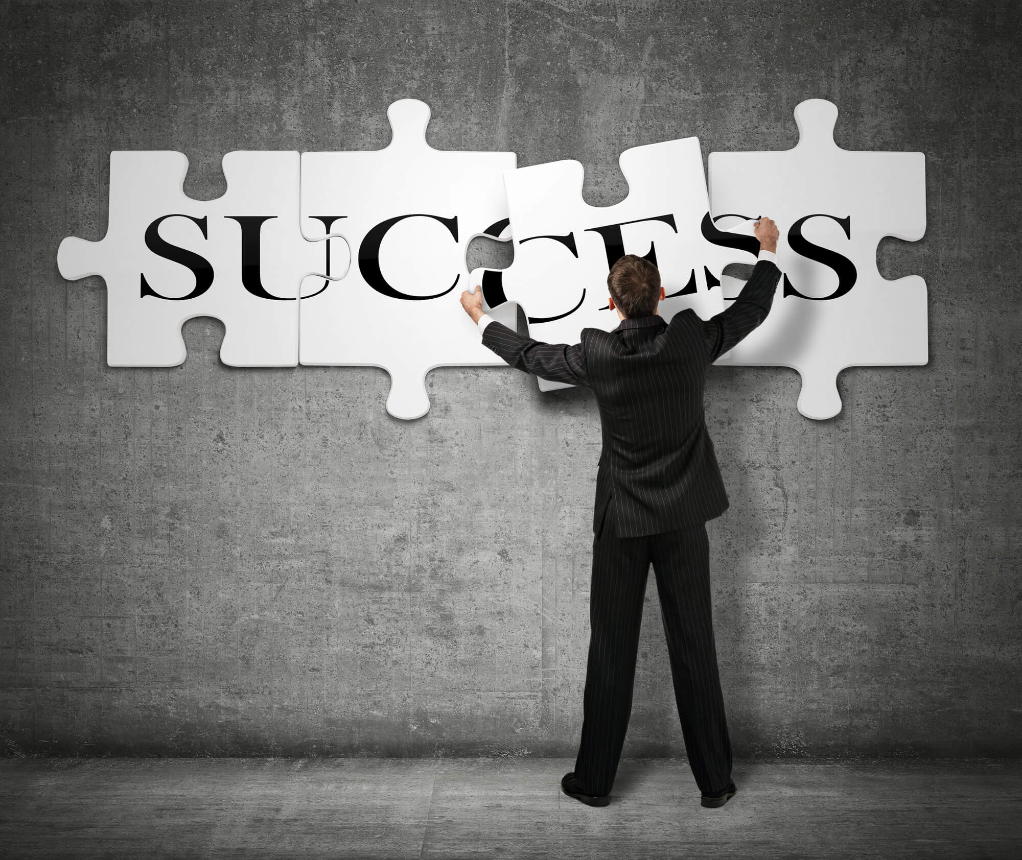 businessman piecing puzzle on wall that spells success