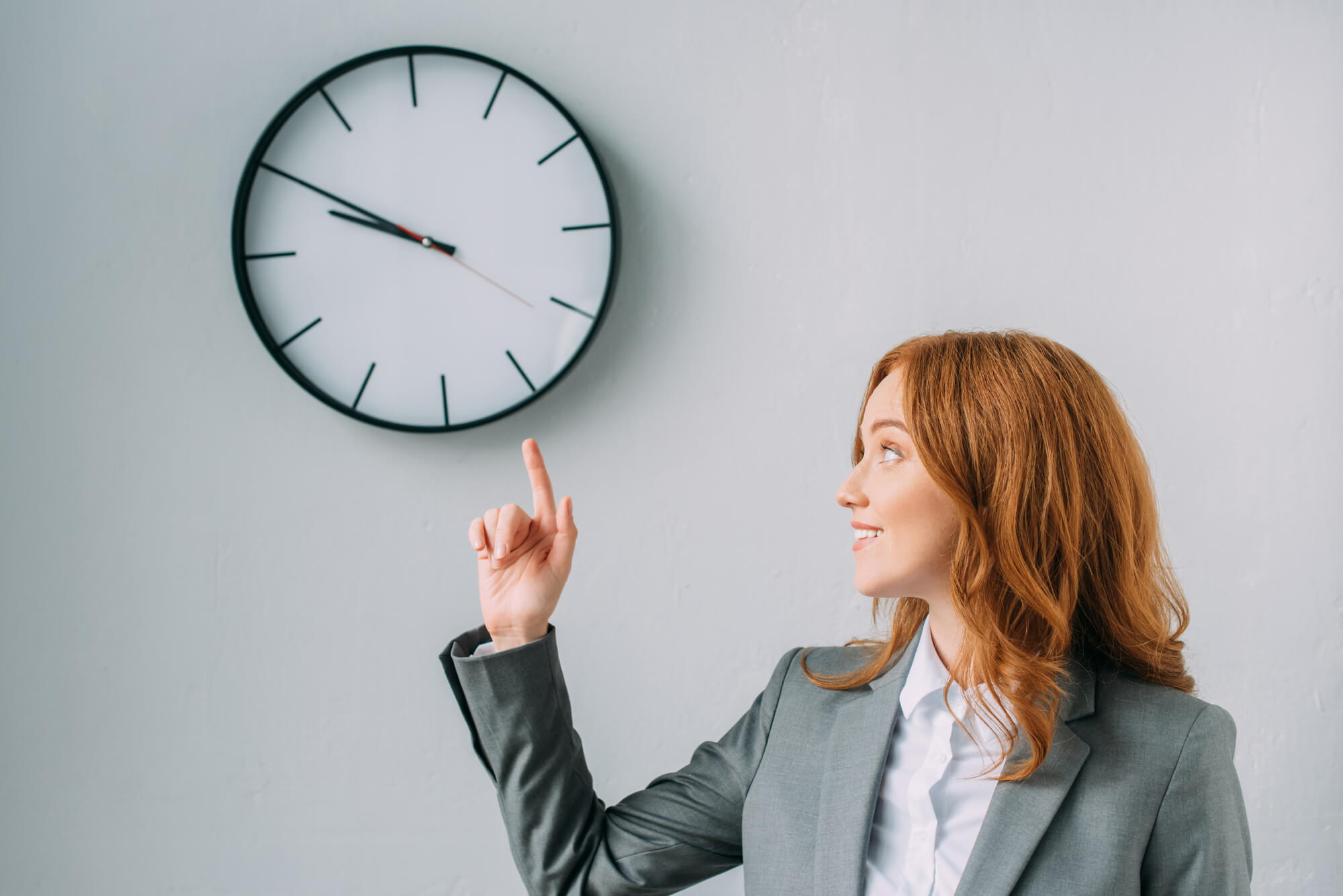 businesswoman pointing at a wall clock