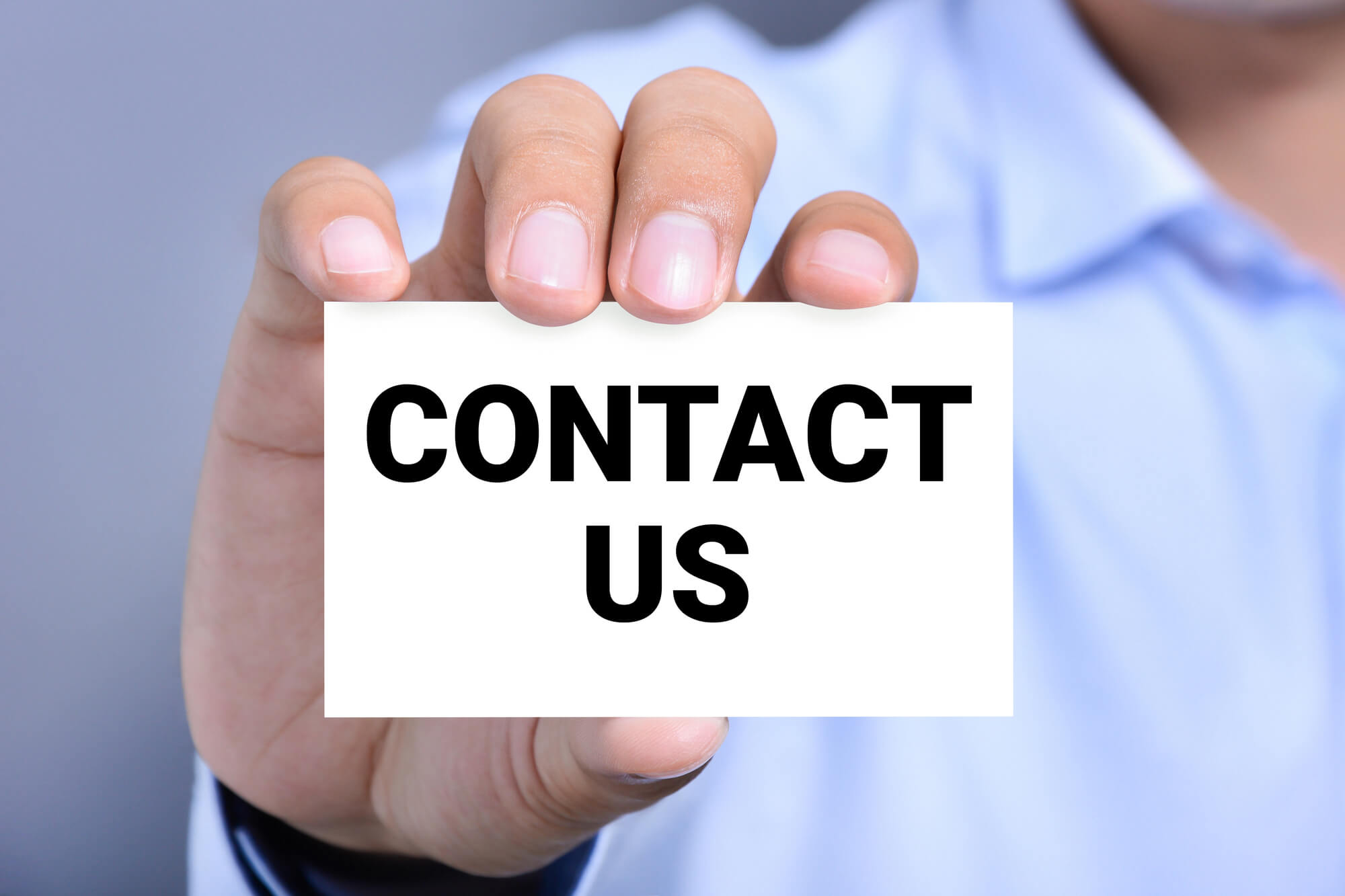 male professional holding a card with contact us written on it