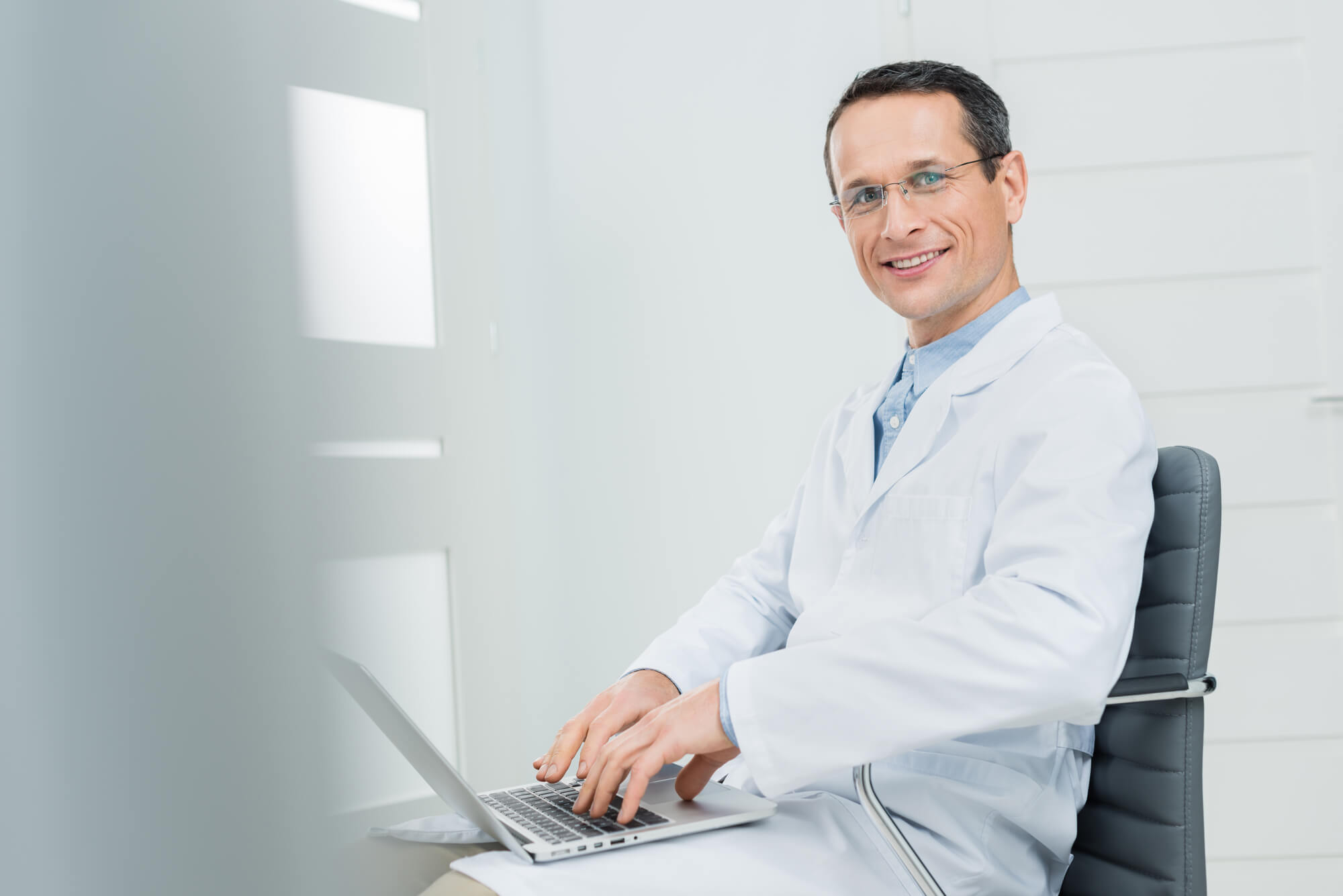 dentist with laptop smiling at the camera 