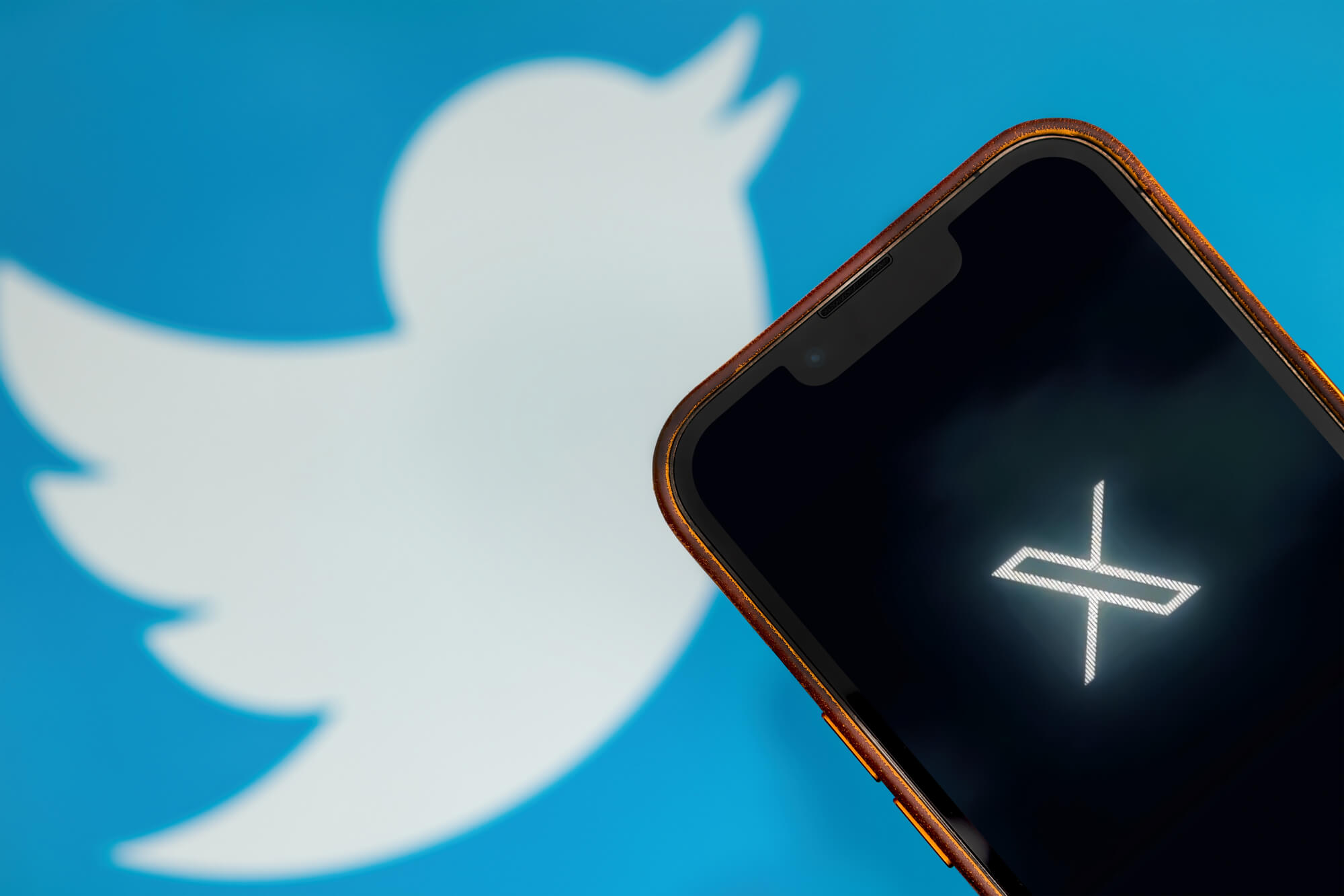 twitter x logo on phone and twitter old logo behind it