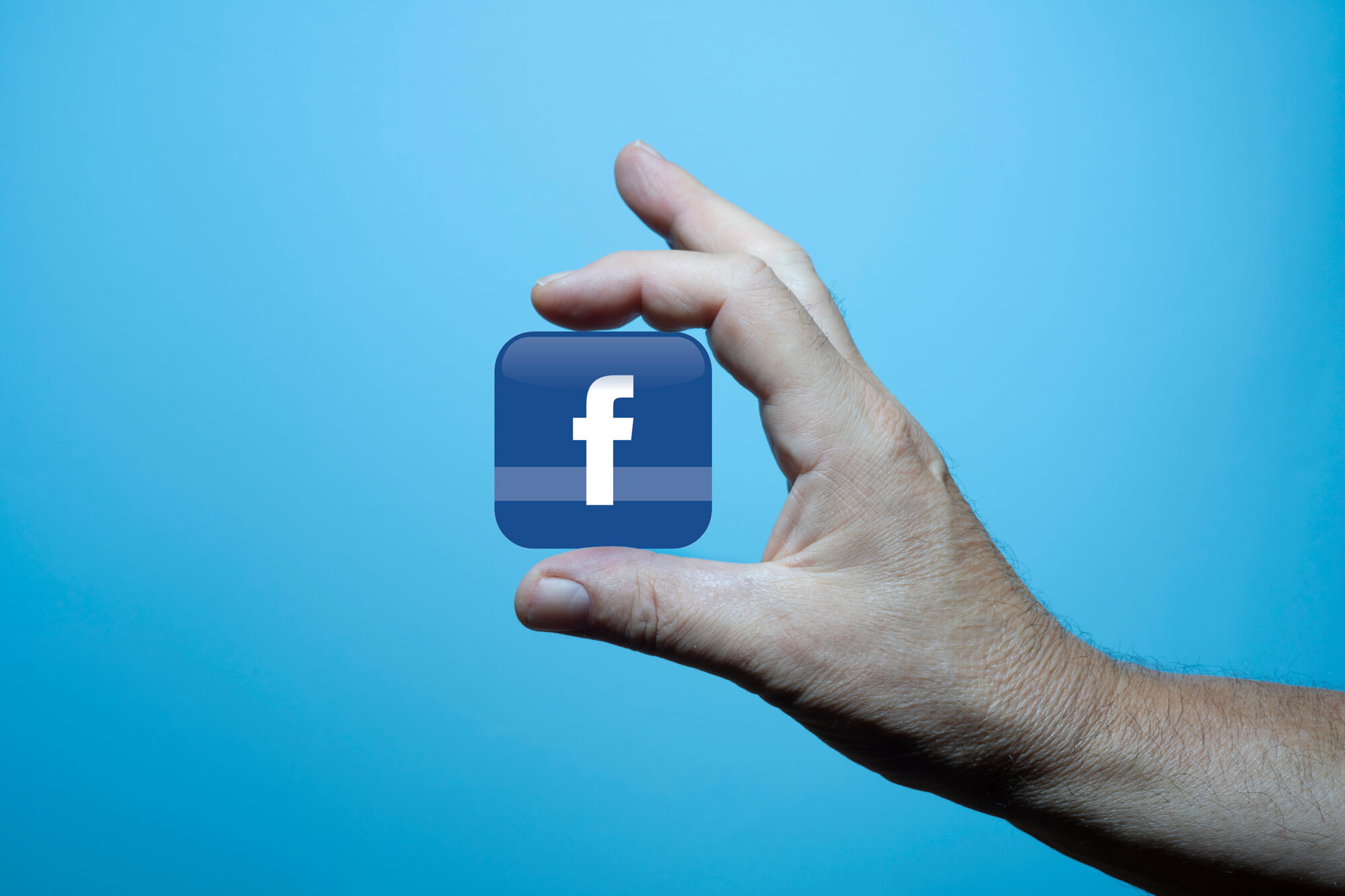 hand holding block with facebook logo