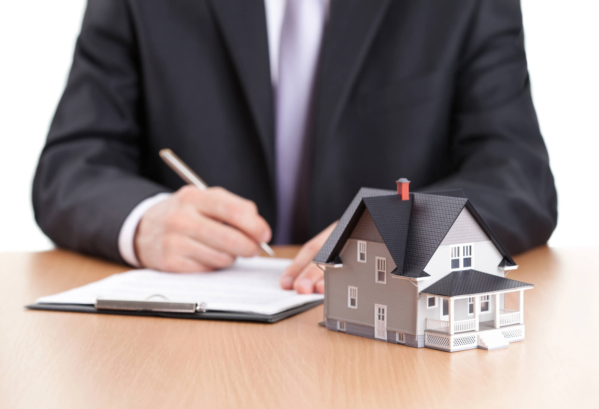 businessman signing contract behind home model