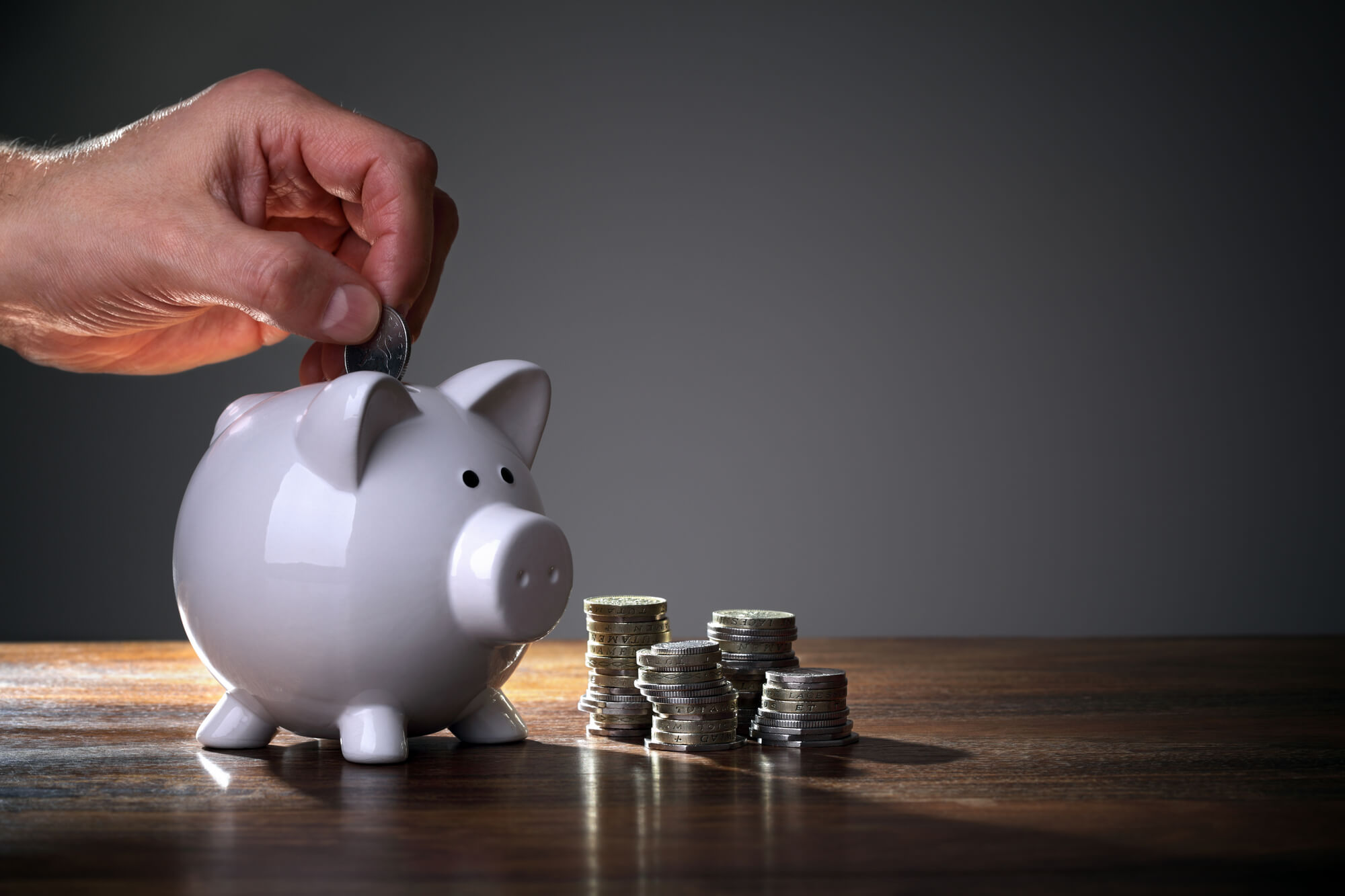 hand dropping coin into piggy bank