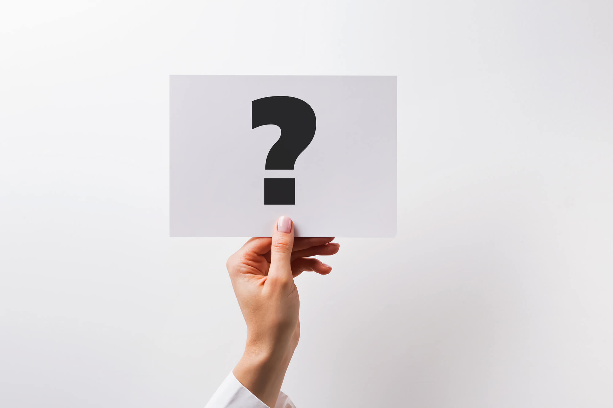female hand holding a paper card with question mark