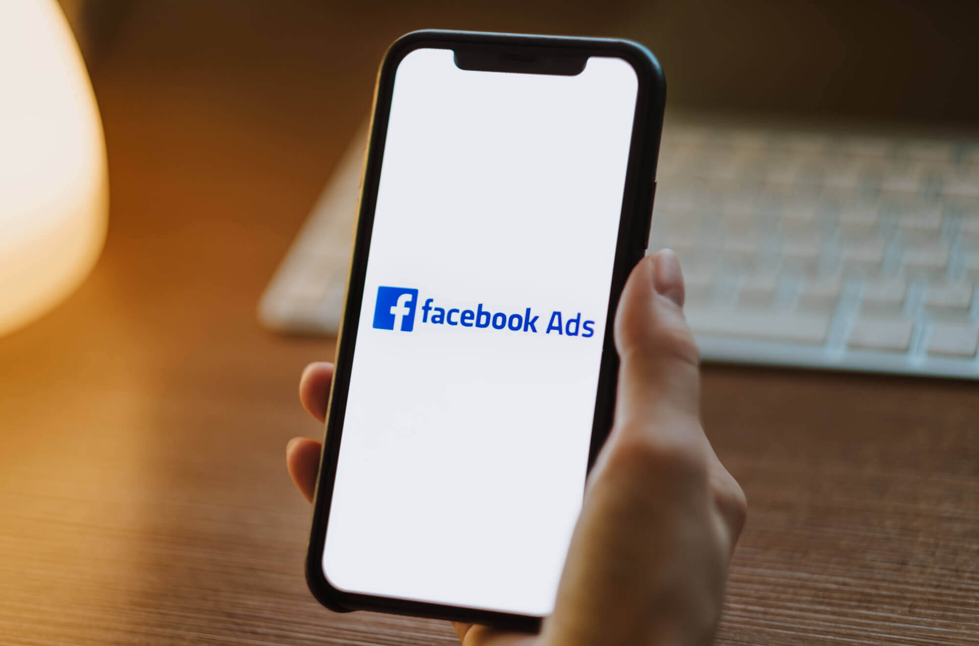 hand holding a smartphone with Facebook Ads on the screen