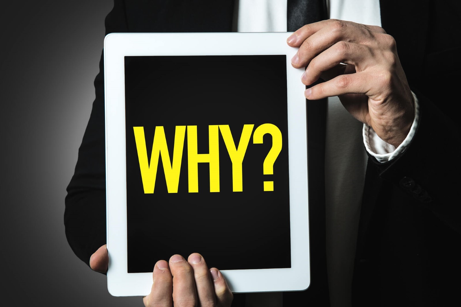 businessman holding a tablet with the word WHY in it