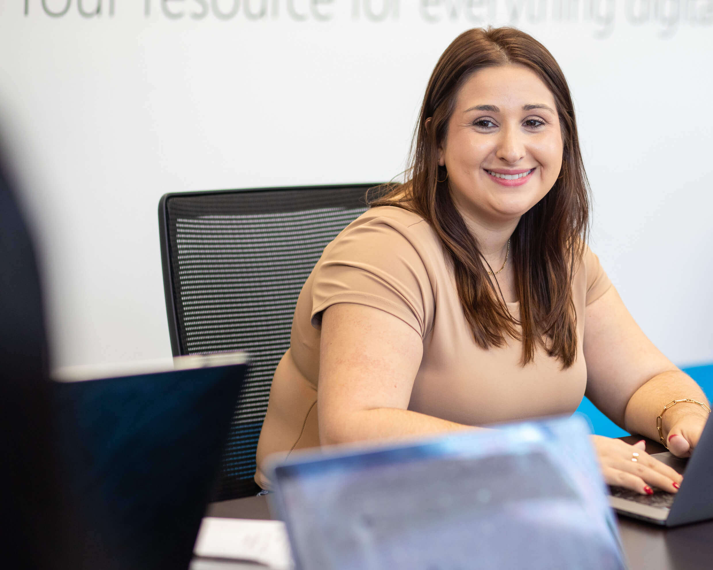 DR account manager posing candidly as she uses her laptop and looks at a colleague 