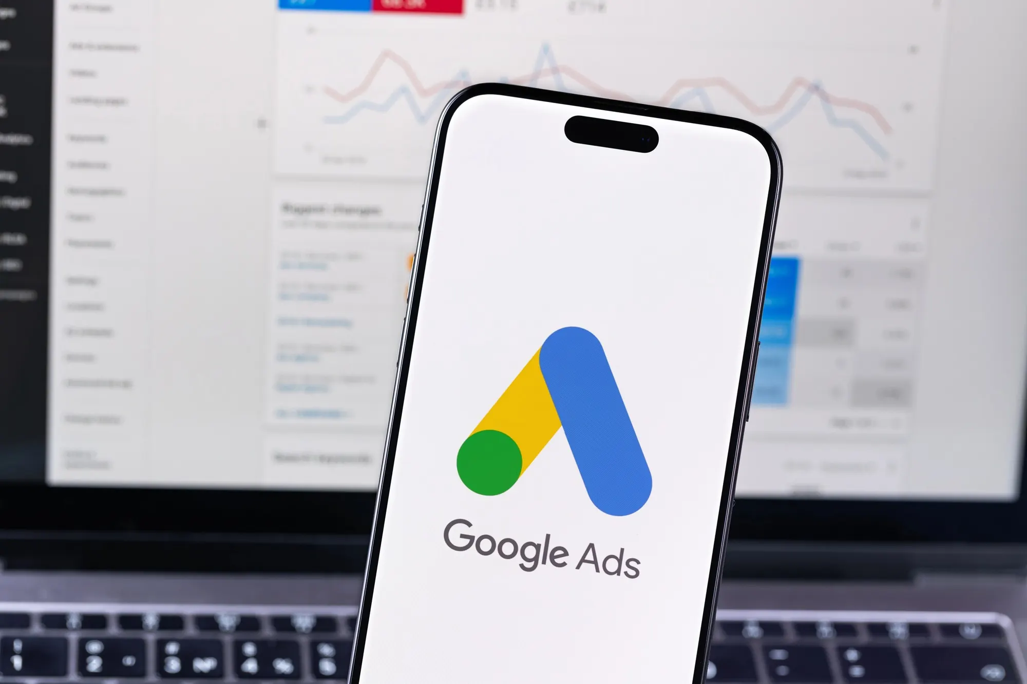 Smartphone displaying the Google Ads logo with campaign analytics in the background, representing lead generation for plumbing marketing strategies