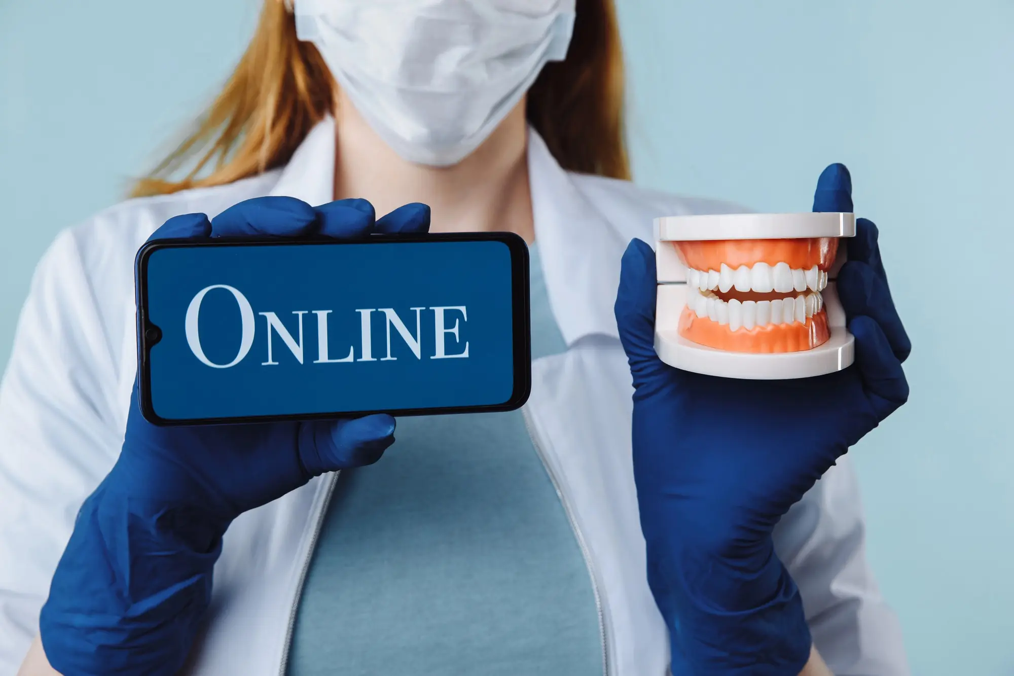 Dental professional holding a phone displaying online services beside a dental model, illustrating getting your practice into AI search results