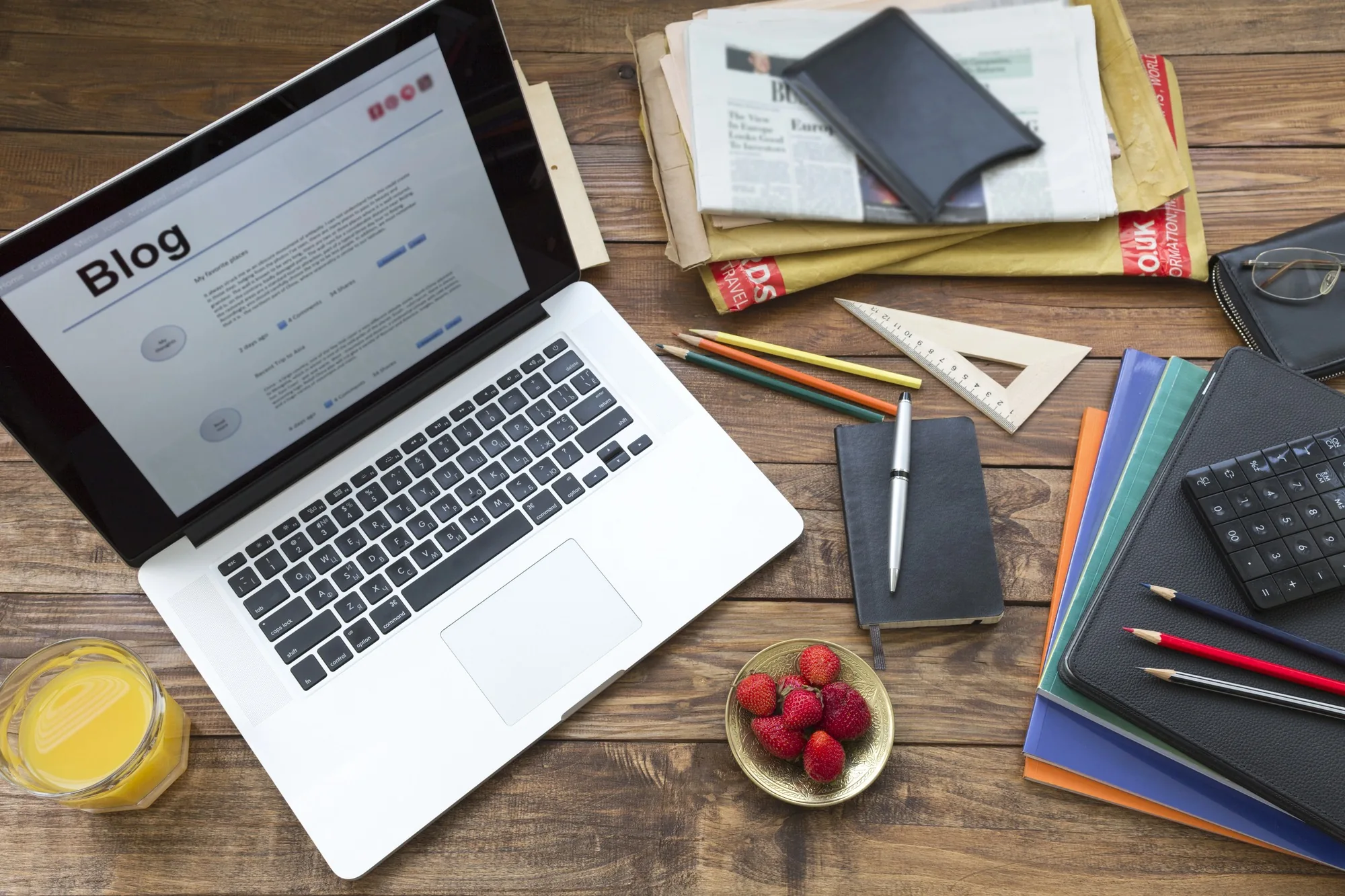 Laptop displaying a blog dashboard on a desk with notebooks and office supplies, representing professional content creation for Beyond Great Content SEO