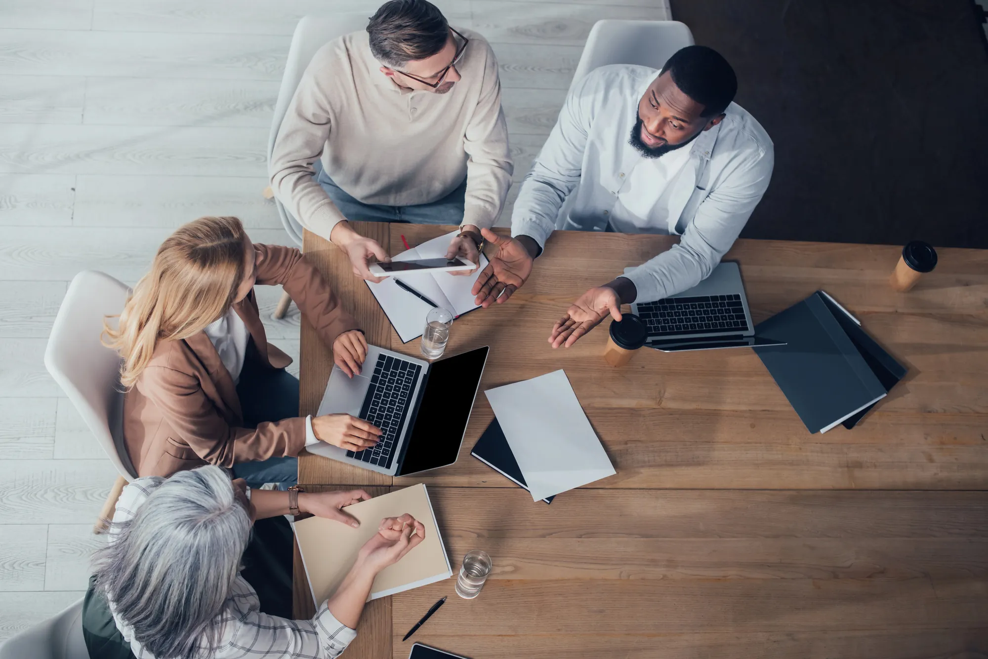 Overhead view of a business team collaborating around laptops and notebooks during a website design meeting