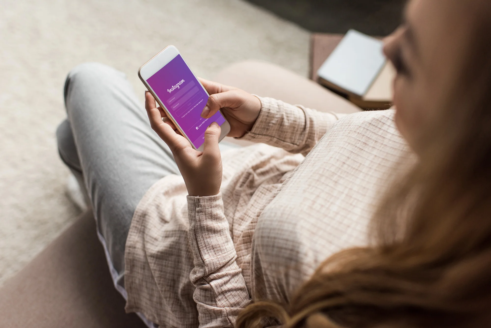 Woman logging into Instagram on her phone at home, representing the DIY side of social media management services