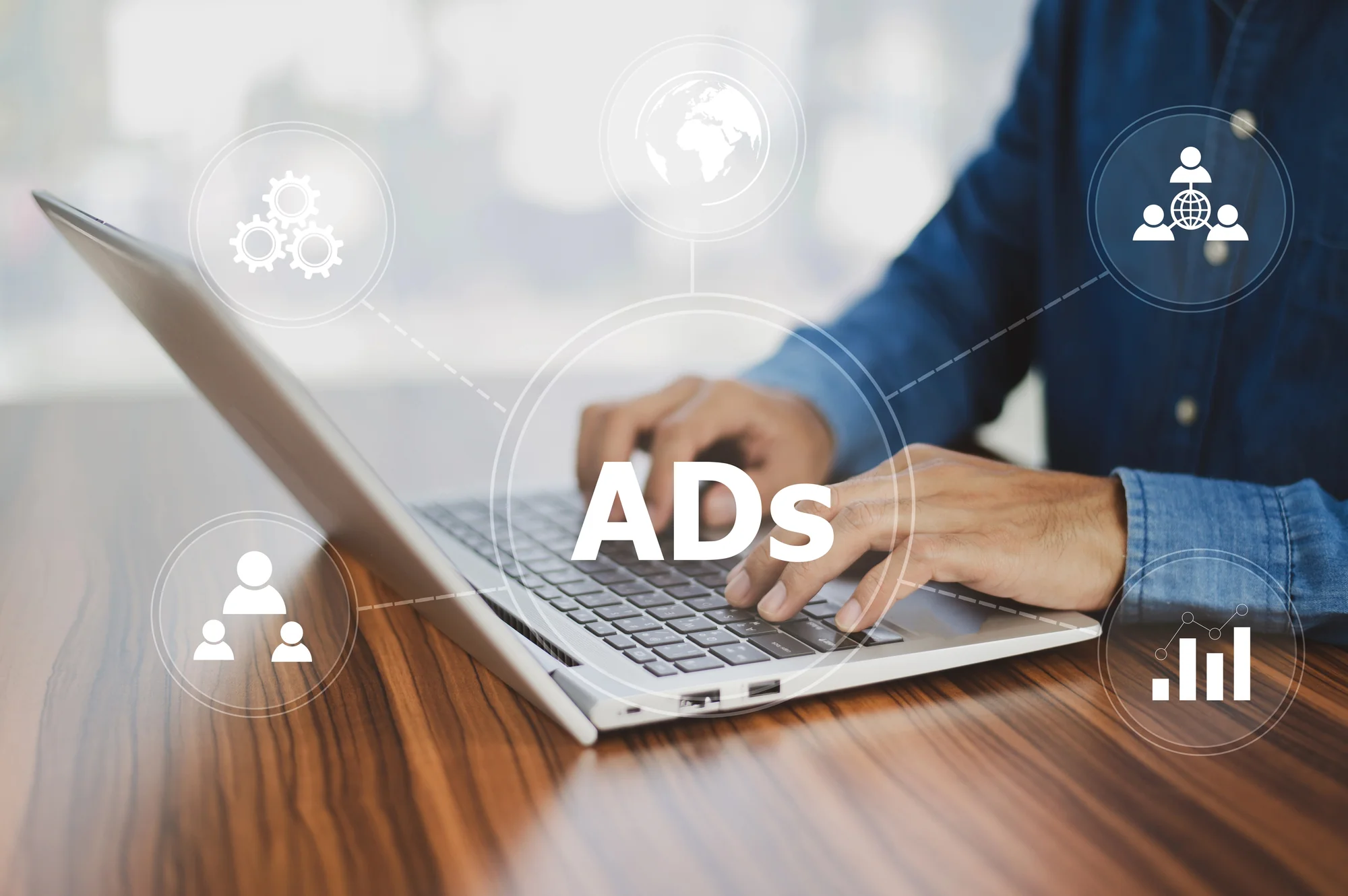 Person typing on a laptop labeled ADs surrounded by icons for audience targeting, reach, and performance tracking managed by a paid search agency