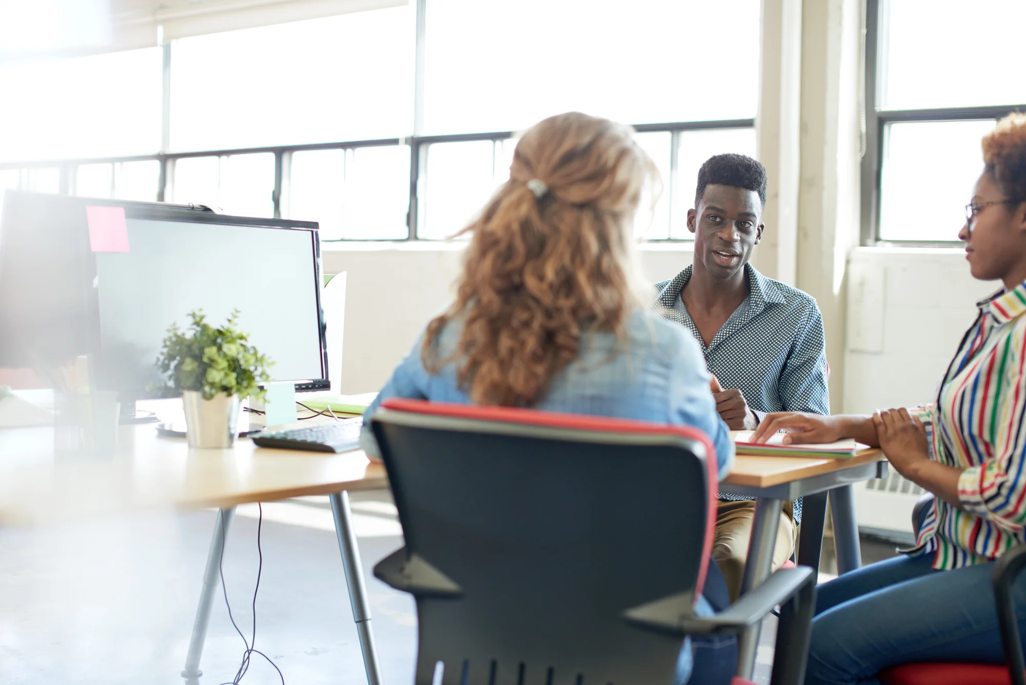 Team discussing marketing strategy at a desk, representing a conversation about bringing in a paid search agency