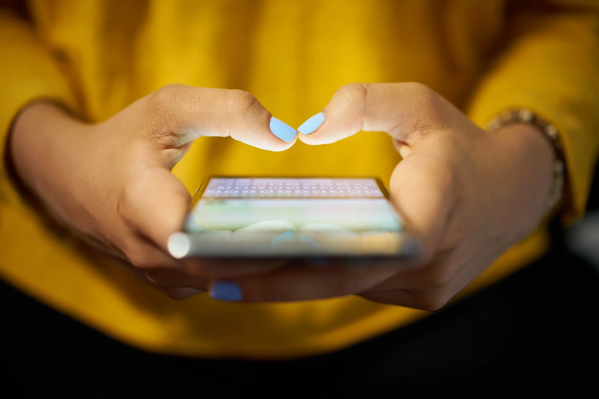 Close-up of hands typing on a smartphone, representing a text message review request sent through review generation services