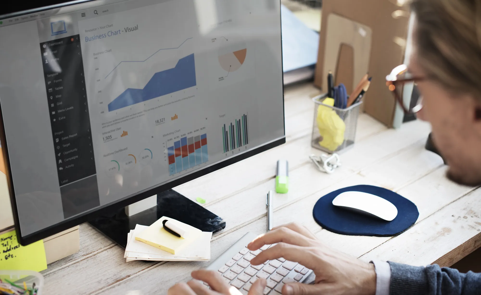 Marketer reviewing a performance analytics dashboard with charts on a desktop monitor, representing data-driven work at a social media strategy agency