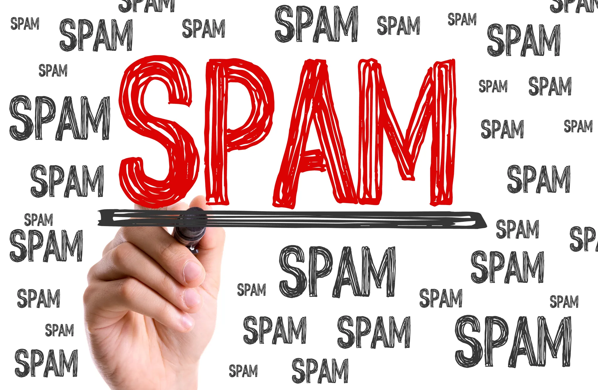 Hand underlining the word spam written in red among repeated spam text, symbolizing how SEO audit services address Google’s two-phase September 2026 spam update