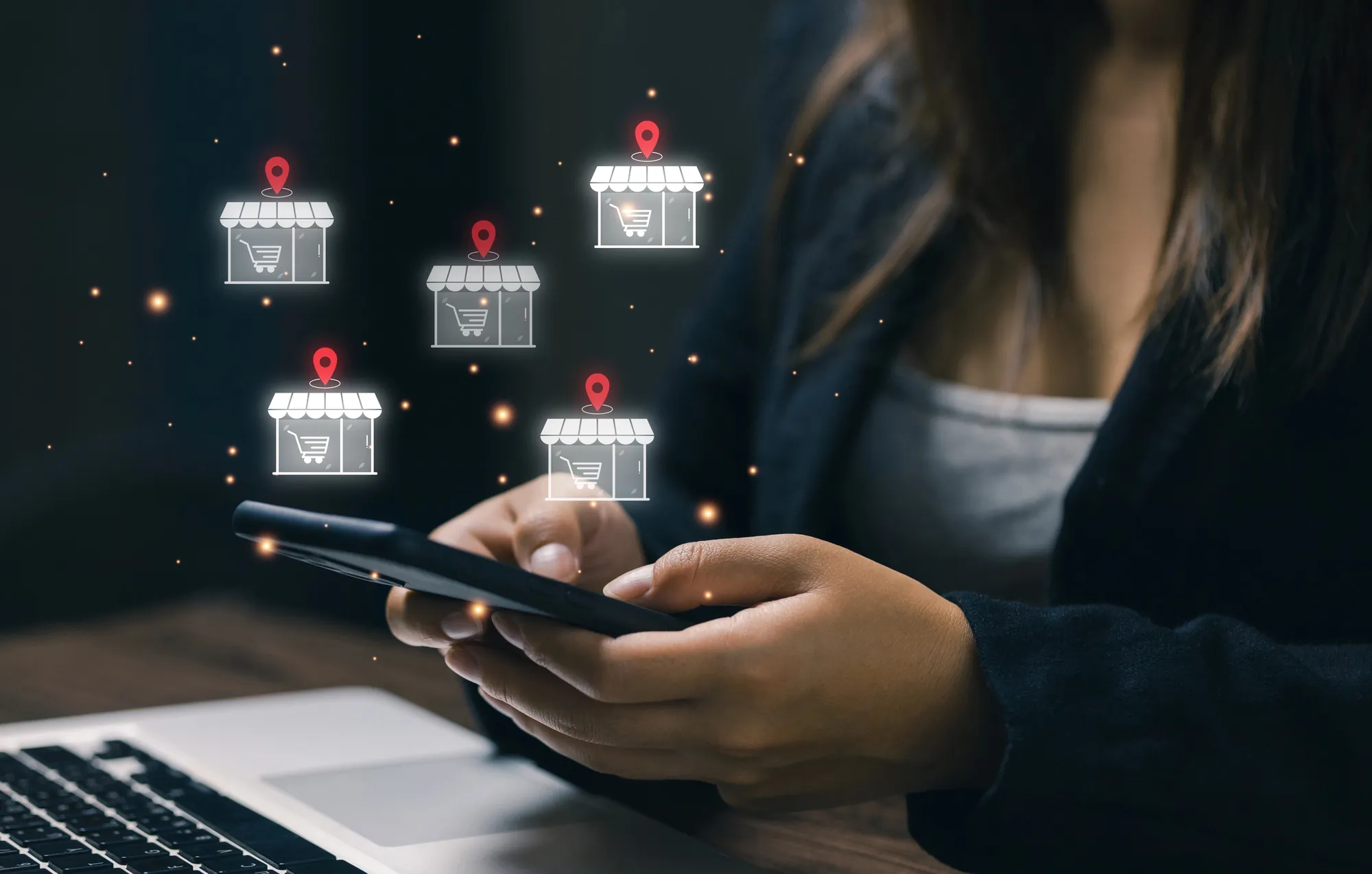 Business professional at a laptop with a digital map of storefronts, customer icons, and location pins around a central audience icon, illustrating multi-location targeting in PPC for franchises