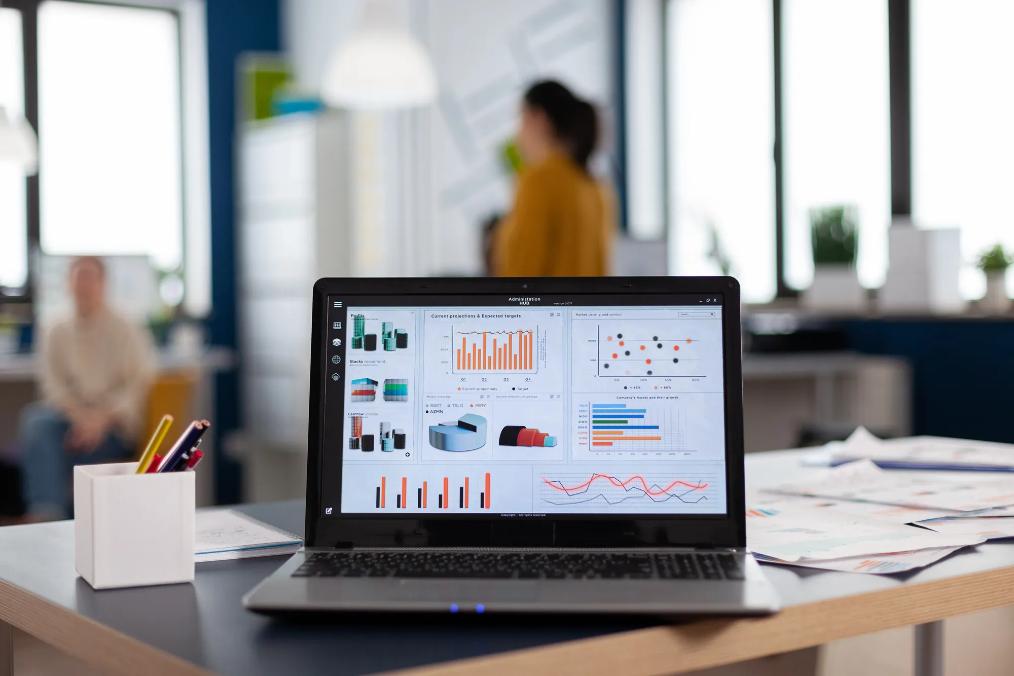 Laptop on an office desk displaying a dashboard of profit, projection, and growth charts, showing the reporting and results that drive digital marketing cost