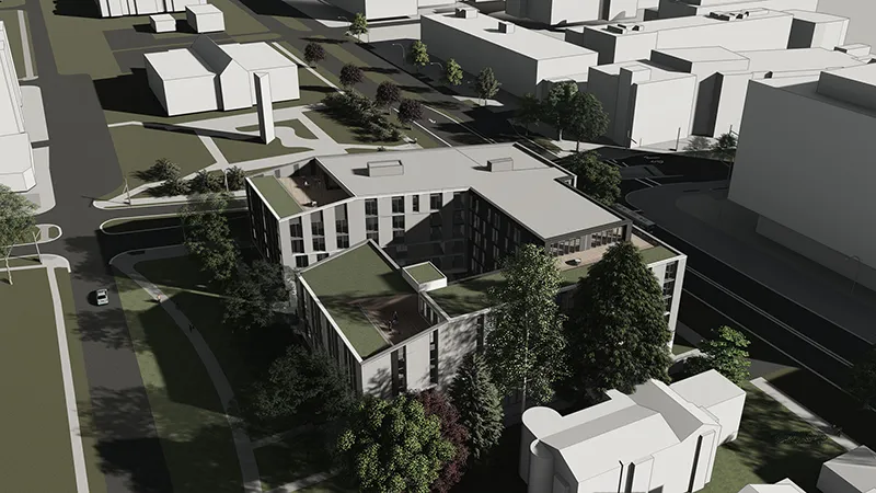 Aerial view of a modern L-shaped building with rooftop greenery surrounded by roads and trees.