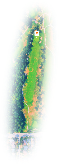 Aerial view of a golf course hole surrounded by trees and adjacent to a residential area.