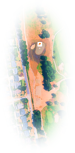 Aerial view of a golf course hole with sand bunkers and adjacent residential area.