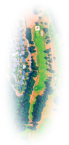 Aerial view of a golf course with a green, sand bunker, and nearby houses on the left side.