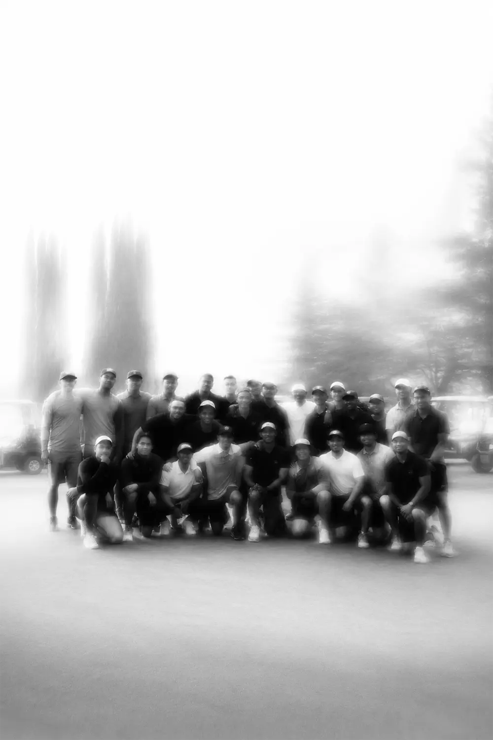 Group of men posing together outdoors, some wearing caps and casual clothing.