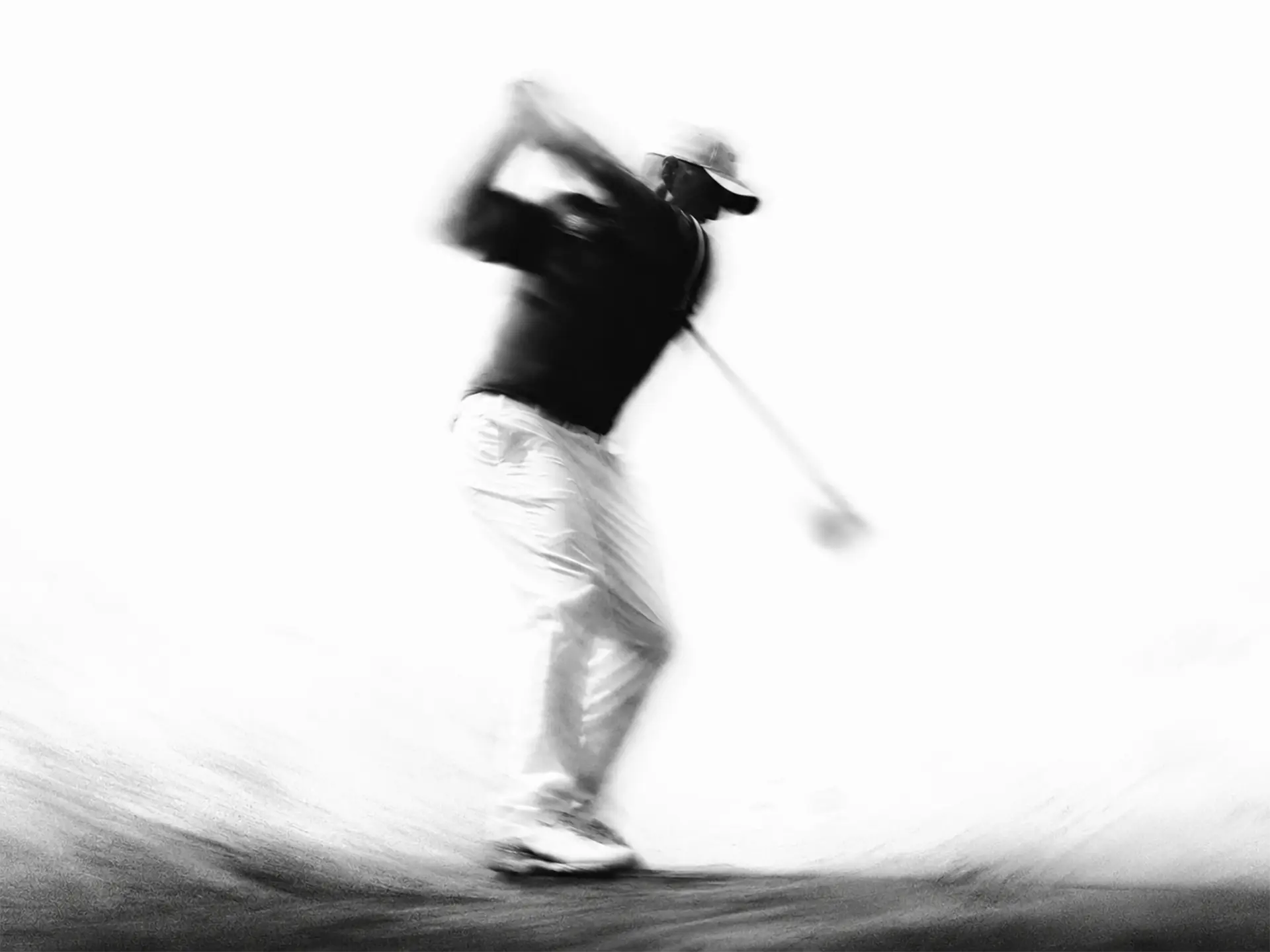 Blurred black and white photo of a golfer swinging a club.